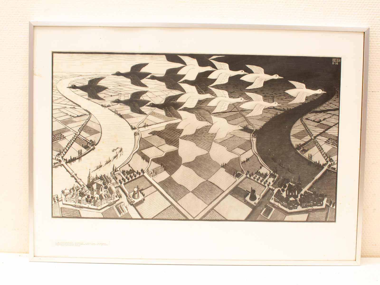 Surreal black-and-white lithograph of a river, geometric fields, birds, and a quaint town.