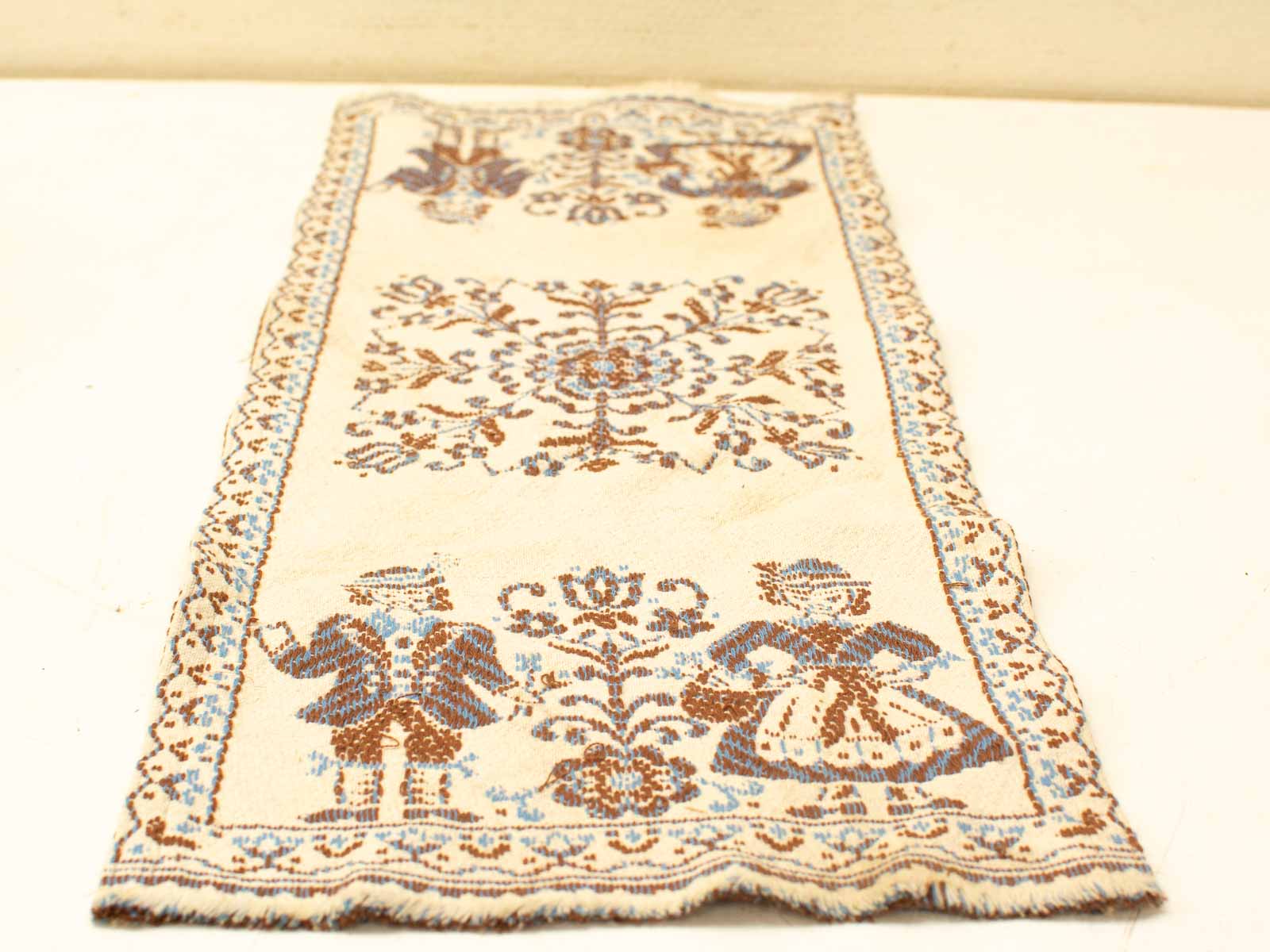 Vintage embroidered textile with folklore figures and floral motifs in rich colors.