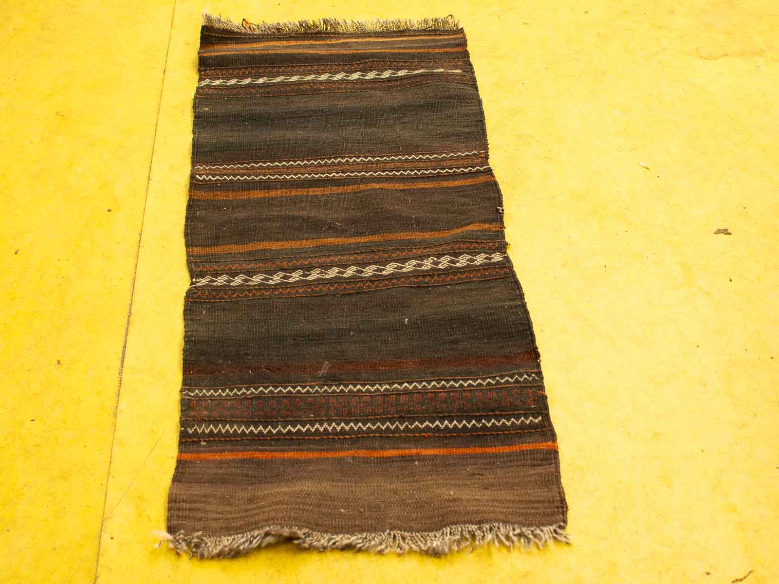 Vibrant handwoven textile in earthy tones with intricate patterns, perfect for rustic decor.