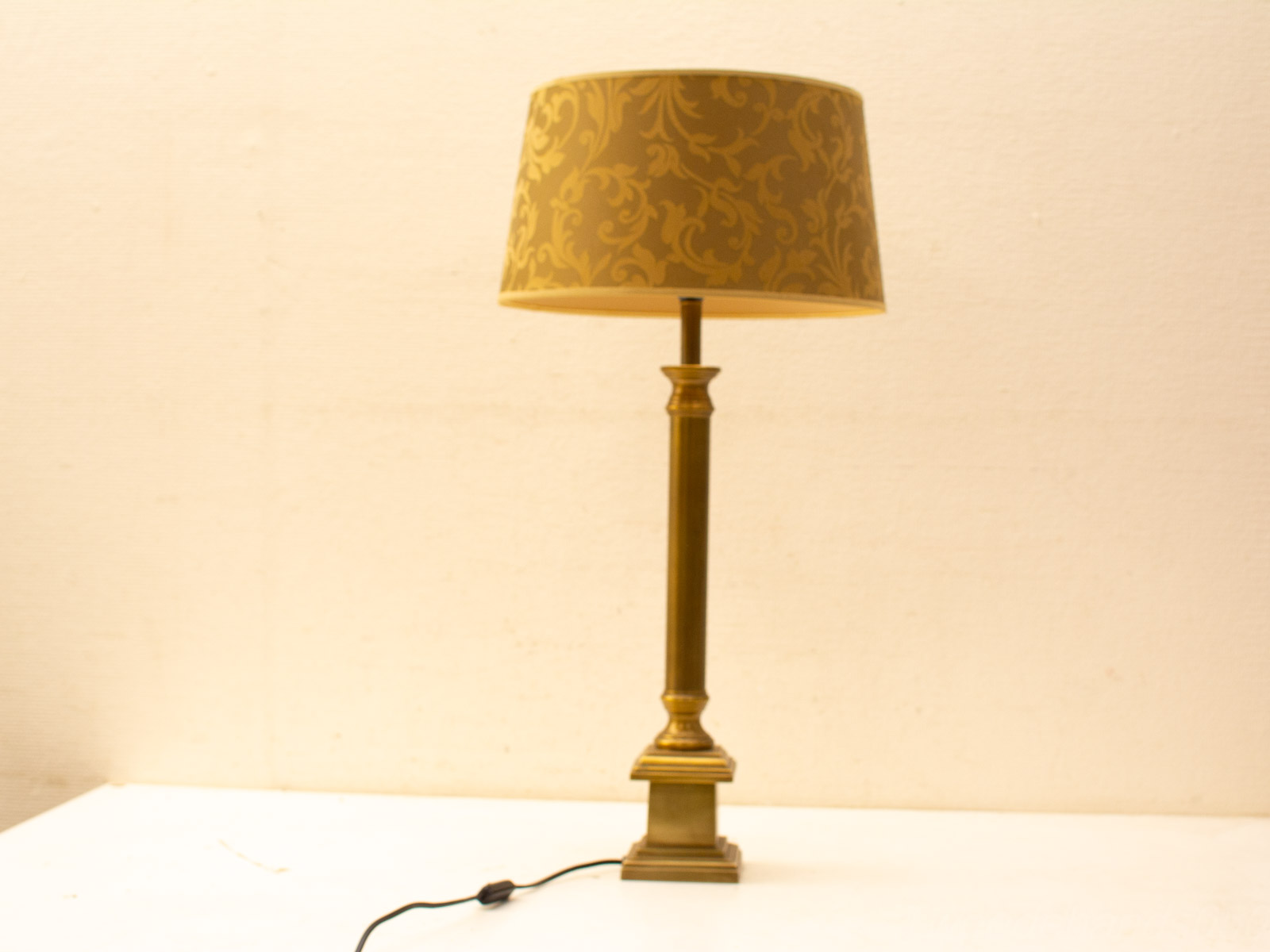 Elegant vintage table lamp with brass base and golden patterned shade for a cozy ambiance.