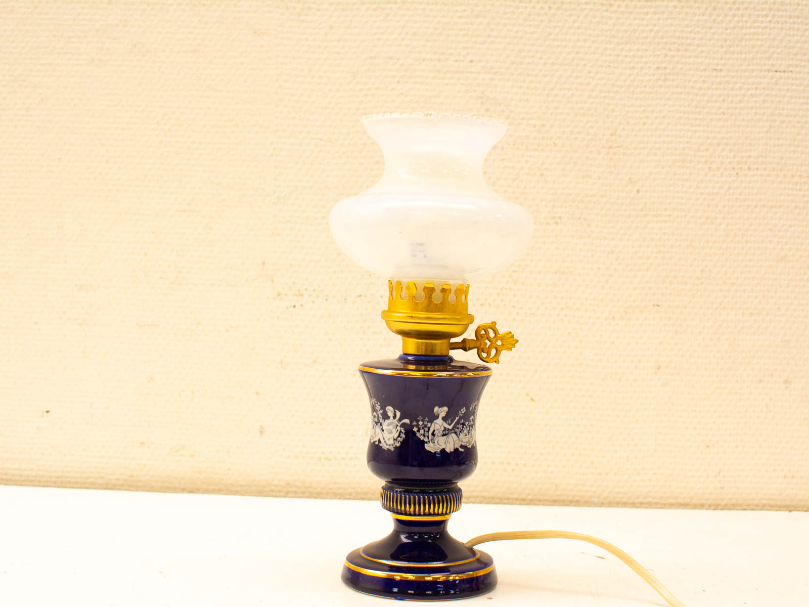 Elegant vintage oil lamp with blue ceramic base, floral patterns, and golden accents. Perfect for cozy spaces.