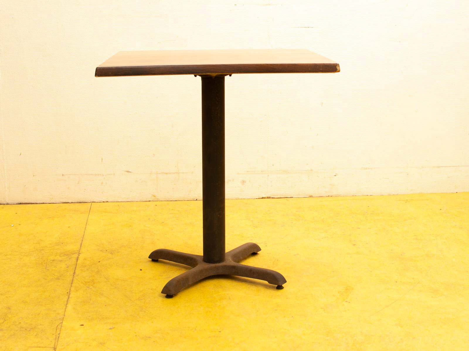 Rustic dark brown wooden table with black metal base, perfect for casual dining or creative work.