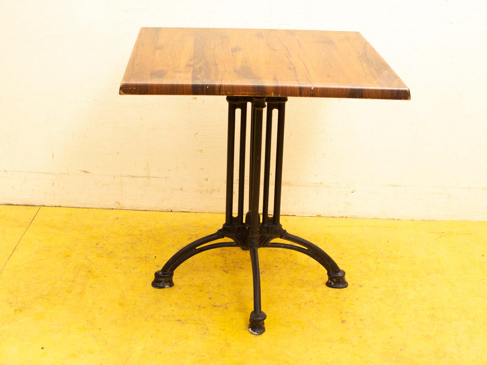 Elegant vintage table with polished wood top and ornate cast iron legs, perfect for cafés.