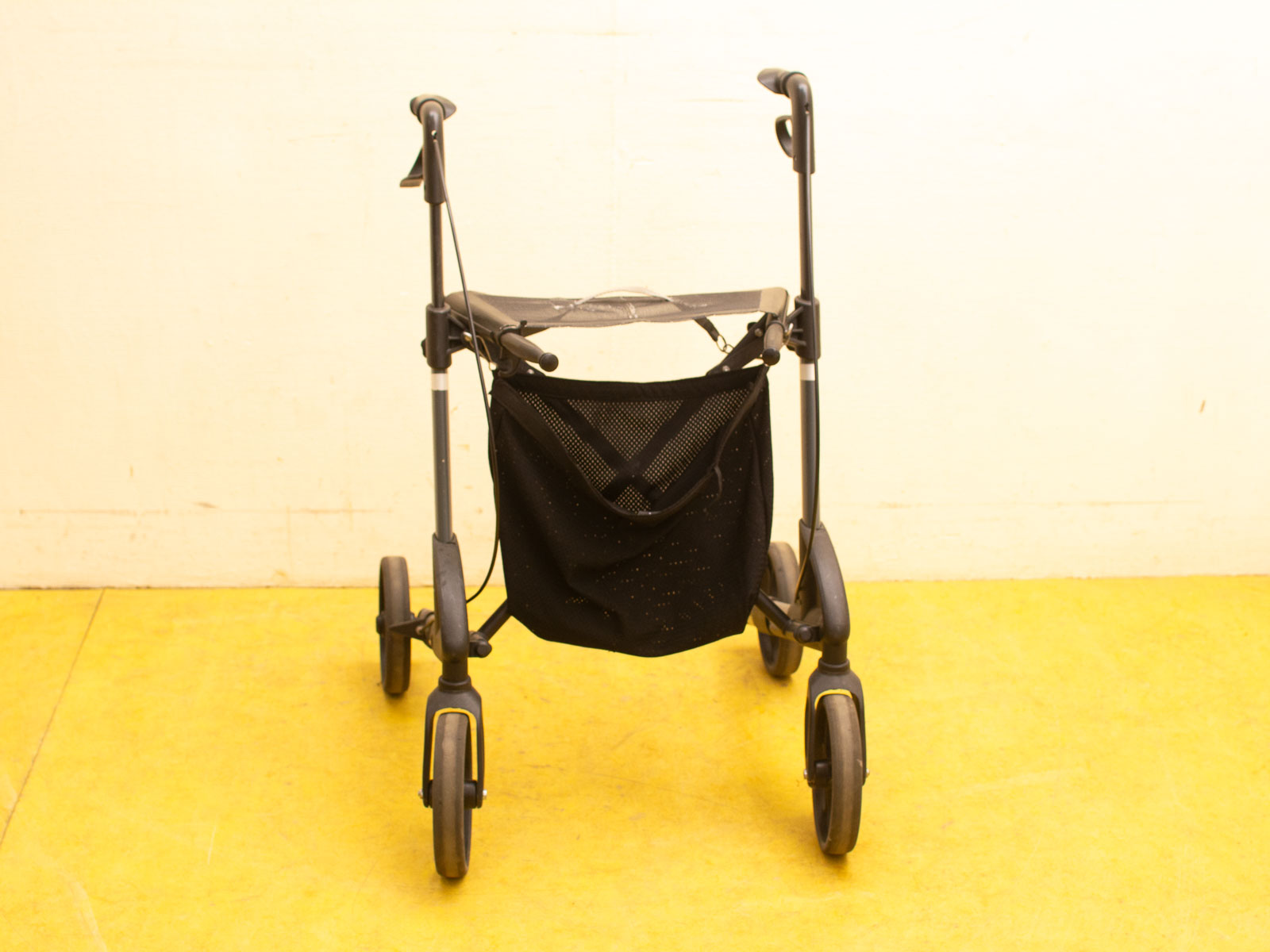 Lightweight black walker with ergonomic handles and practical storage bag for easy mobility and stability.