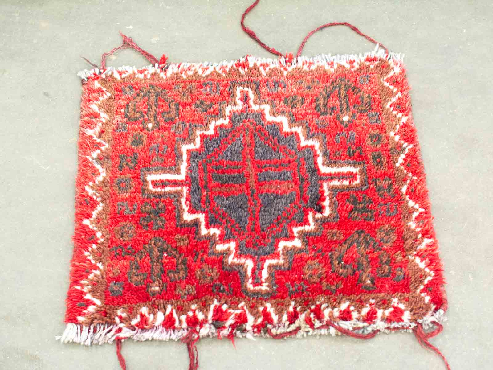 Vibrant red handmade textile rug with intricate geometric patterns and central motif.