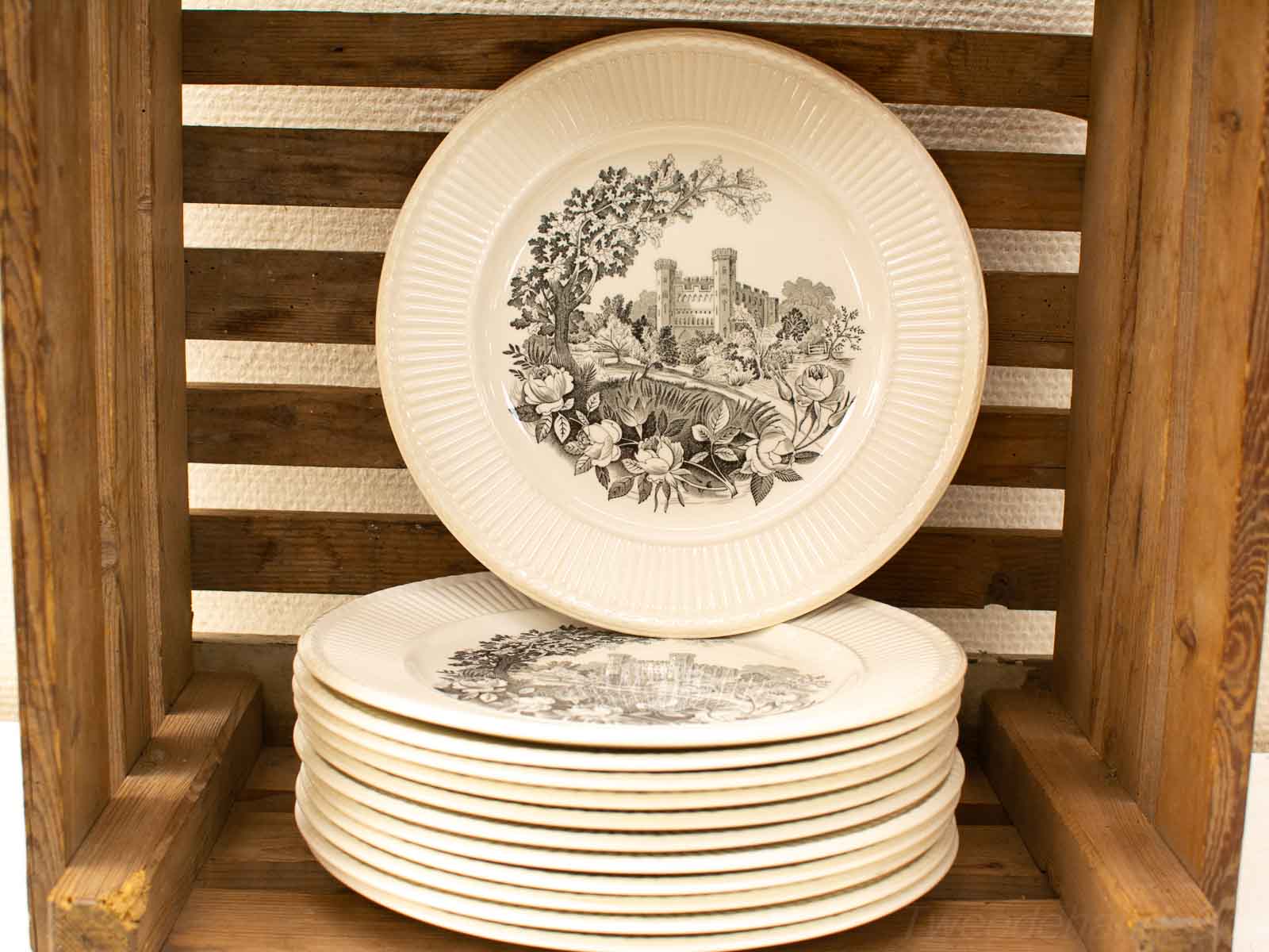 Charming vintage porcelain plates with intricate designs, elegantly arranged in a rustic wooden crate.