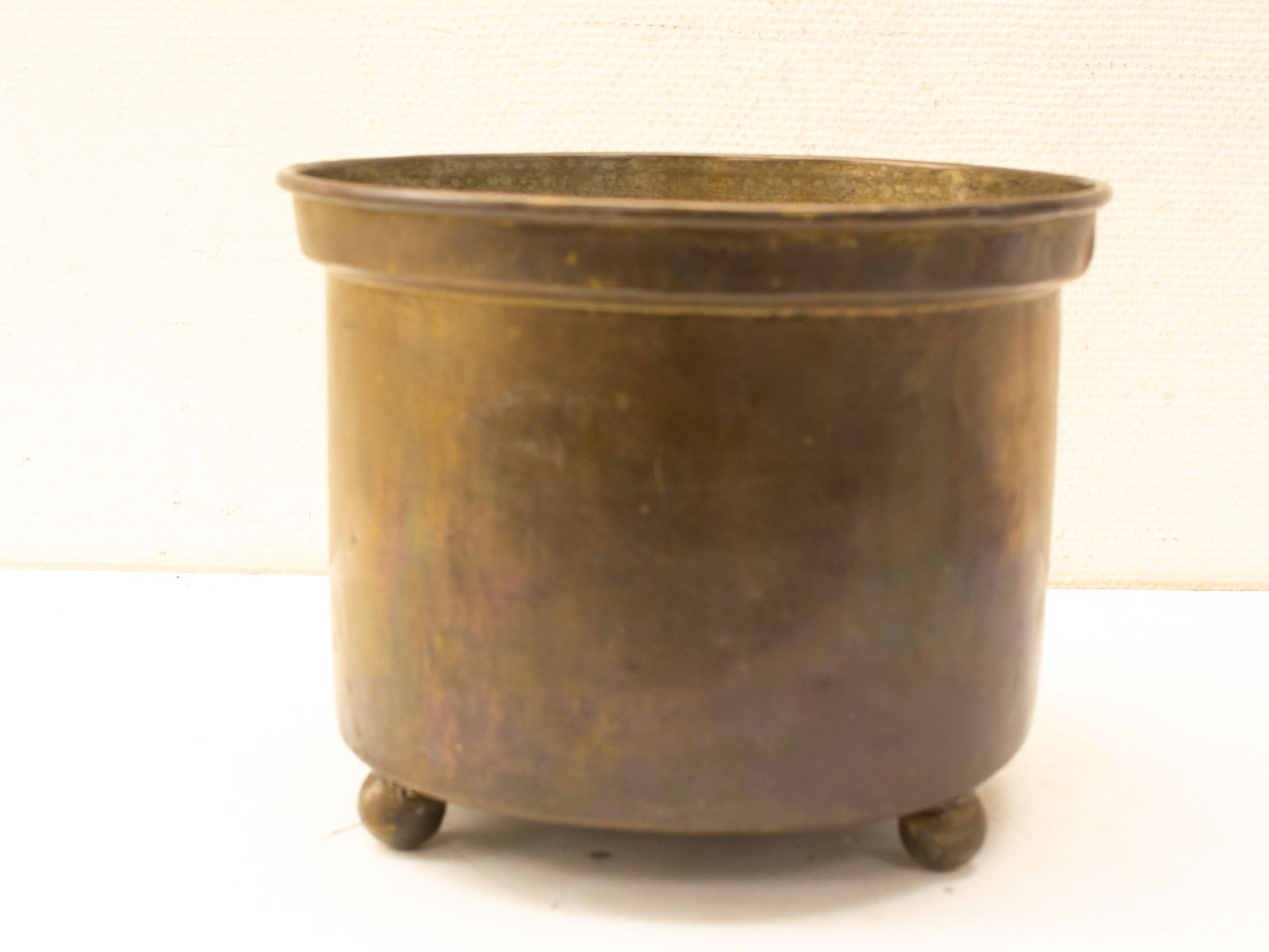 Elegant antique brass pot with spherical feet, perfect for decor or culinary use.