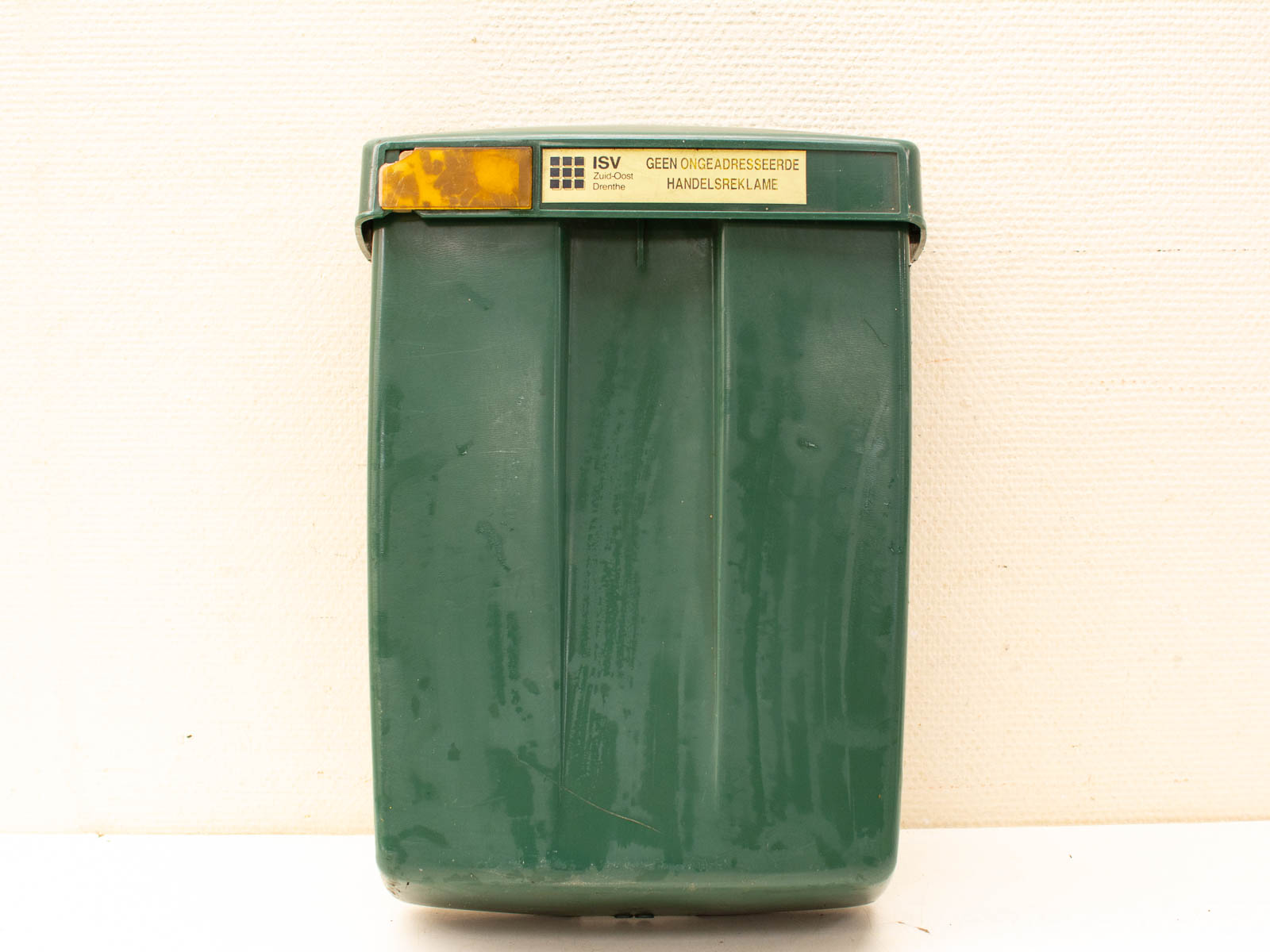 Vintage green plastic postbox with wear and labels, perfect for mail delivery or decorative storage.