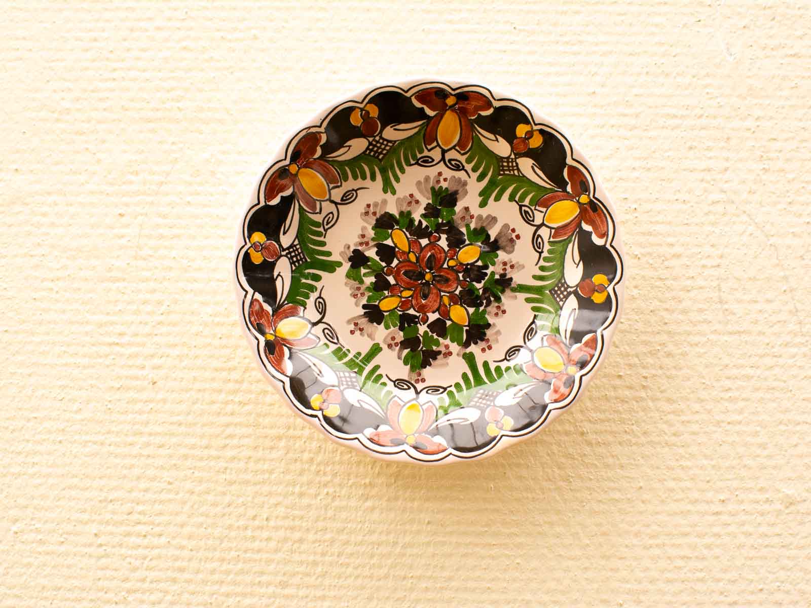 Handcrafted vintage ceramic plate with vibrant floral design and scalloped edge. Perfect decor accent.