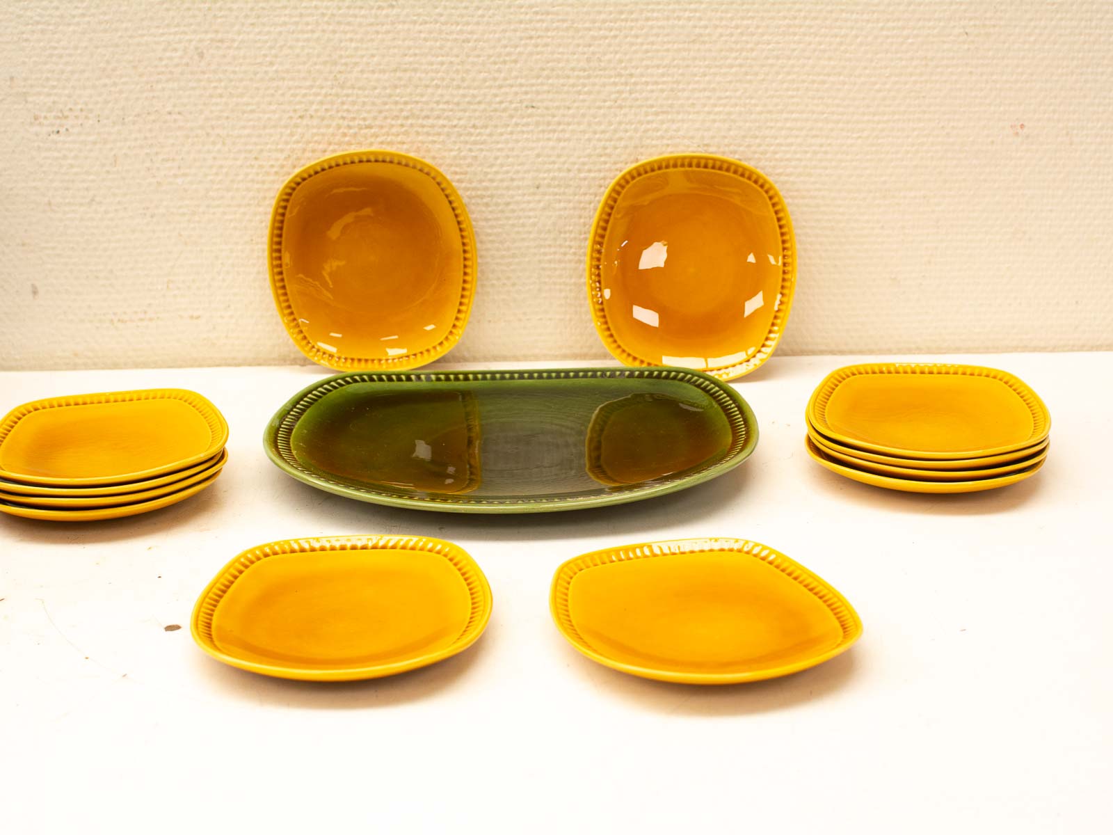 Cheerful vintage yellow ceramic plates with a glossy green serving dish, ideal for festive meals.