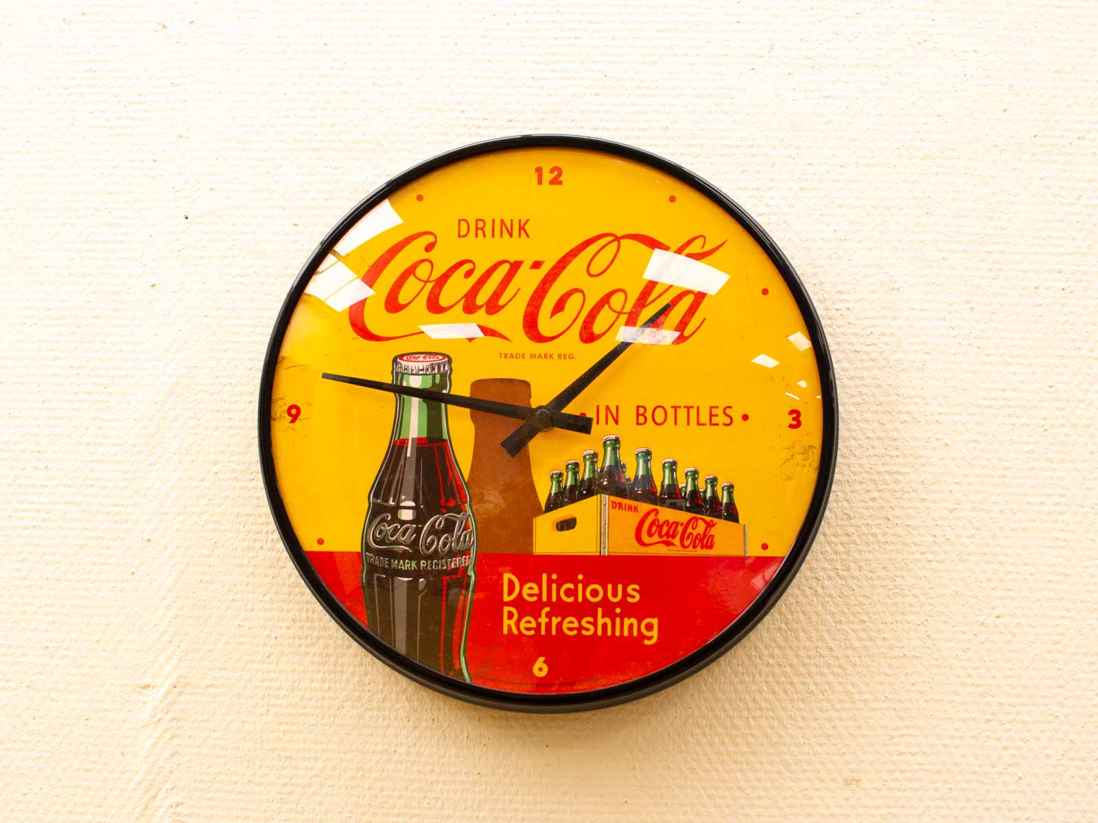 Vintage Coca-Cola Wall Clock with vibrant yellow face, detailed bottle illustrations, and bold retro design.