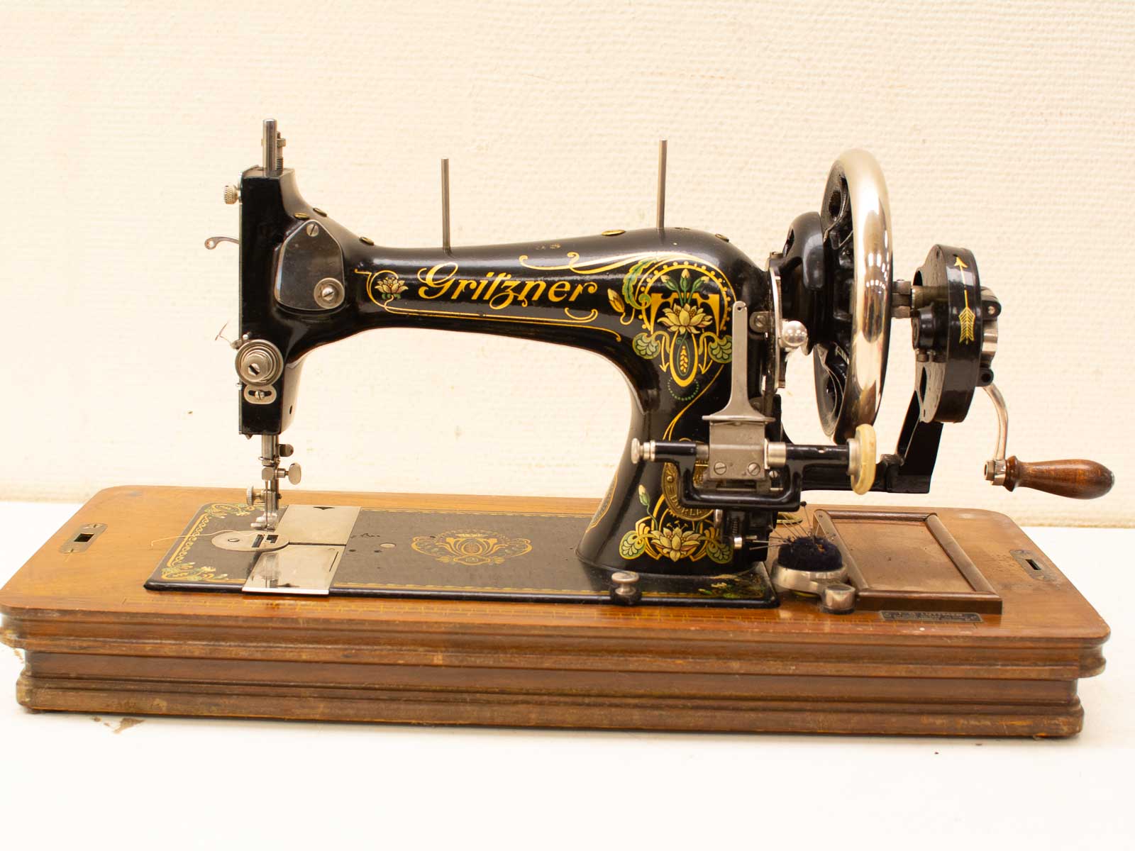 Vintage Gritzner sewing machine with ornate gold designs, mounted on a stylish wooden base.