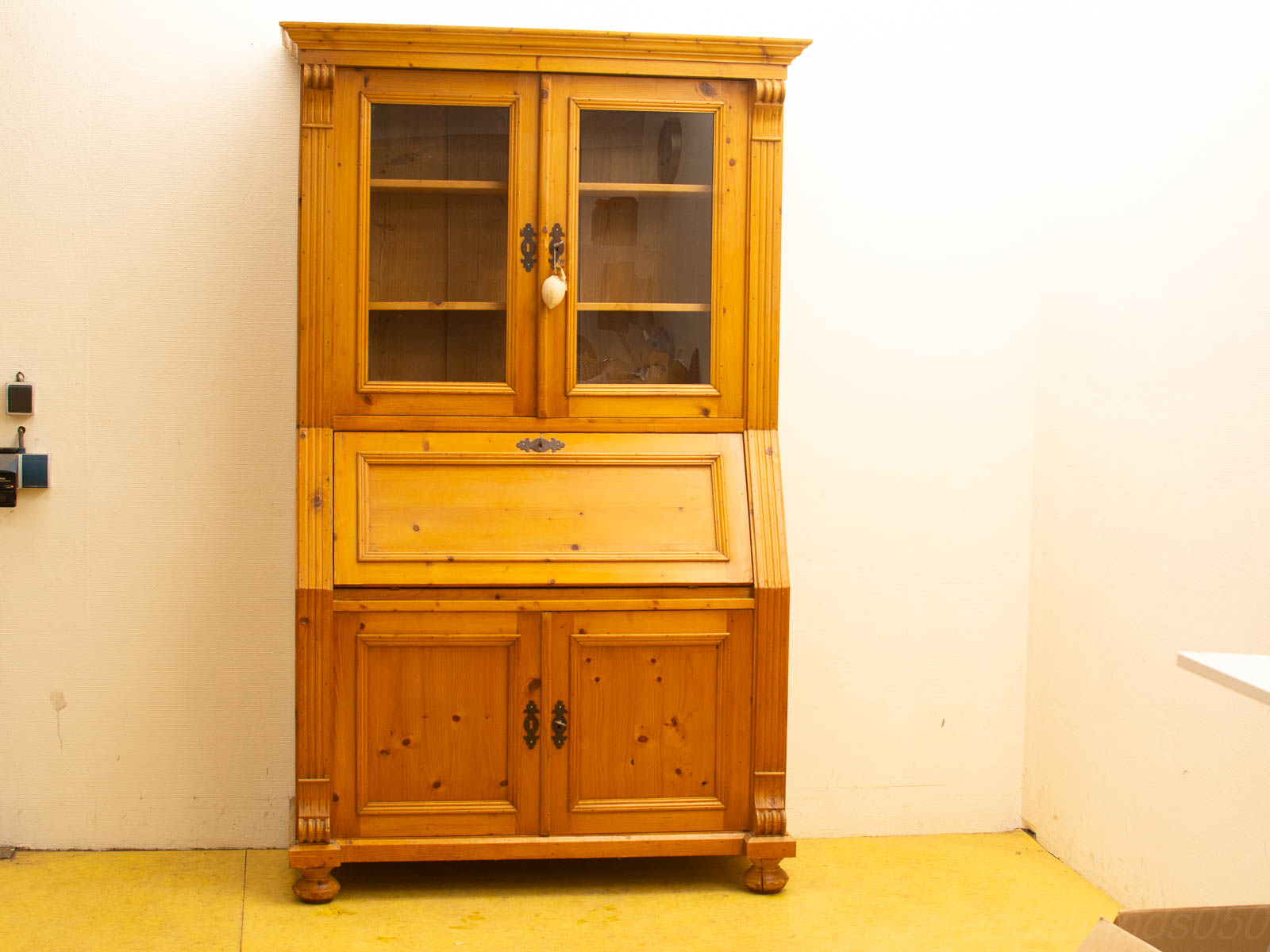 Vintage wooden cabinet with glass doors and writing panel, ideal for rustic to modern interiors.