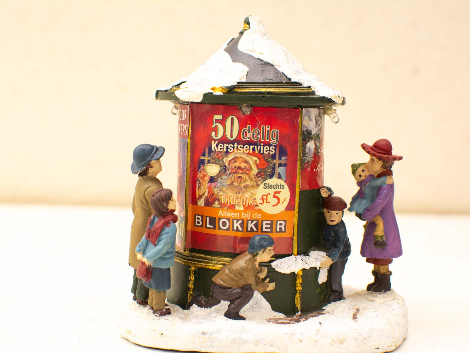 Vintage holiday kiosk figurine scene featuring joyful children and festive decorations in faux snow.