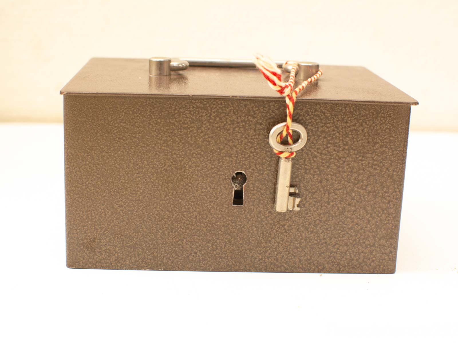 Charming vintage lockbox with key, rustic brown finish, and central metal handle for secure storage.