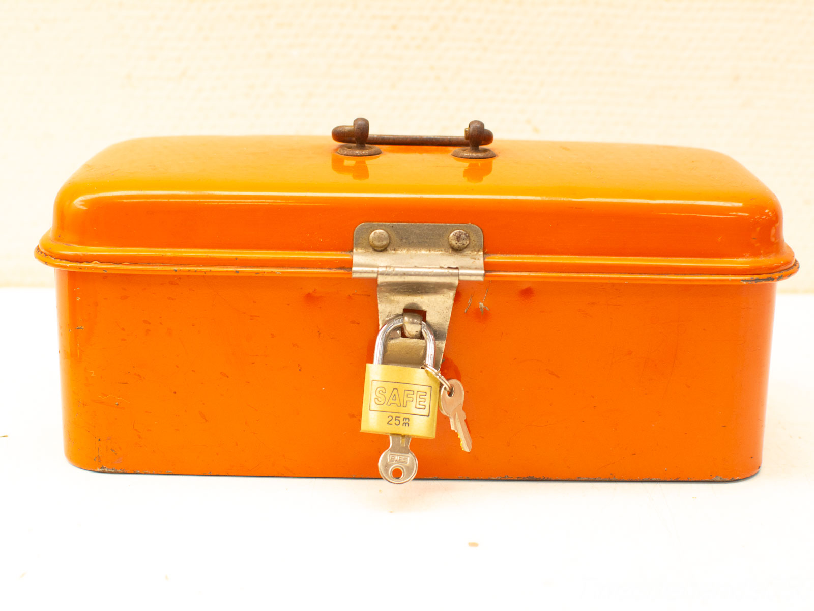 Antique orange lockbox with keys, showcasing vintage charm and practical storage solution.