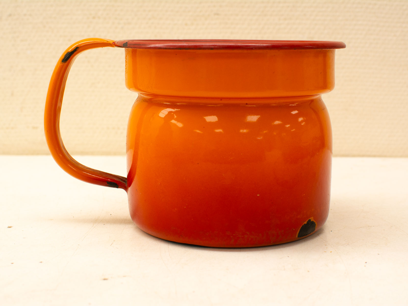 Vintage orange mug with playful red rim, sturdy handle, and charming wear, ideal for retro kitchens.