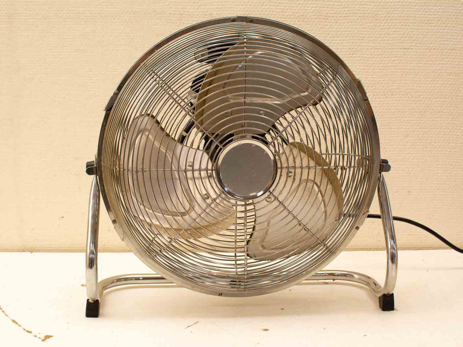 Sleek vintage chrome metal fan with intricate grille and three blades for stylish cooling.