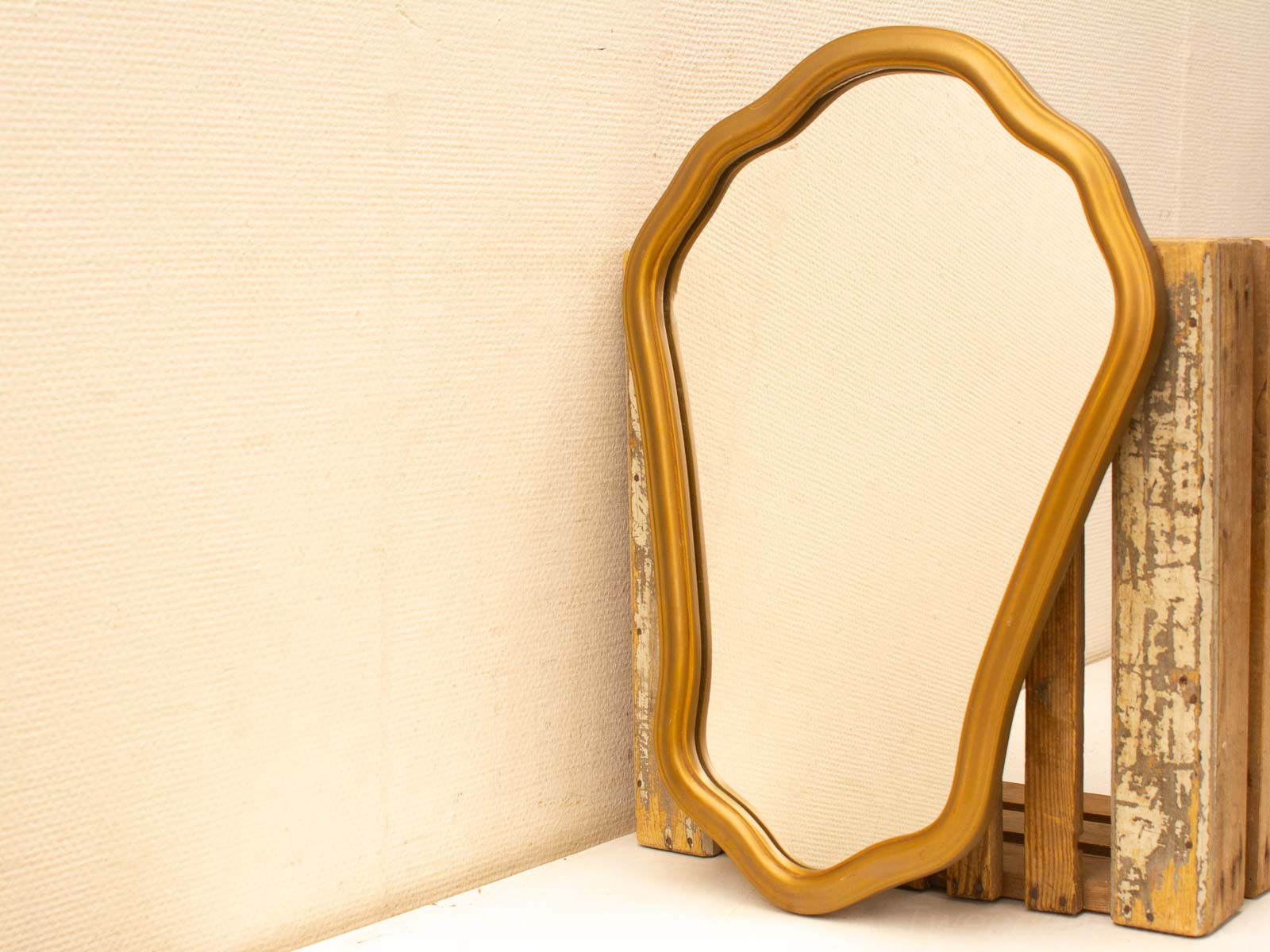 Elegant vintage mirror with gold frame beside rustic wooden crates for timeless charm.