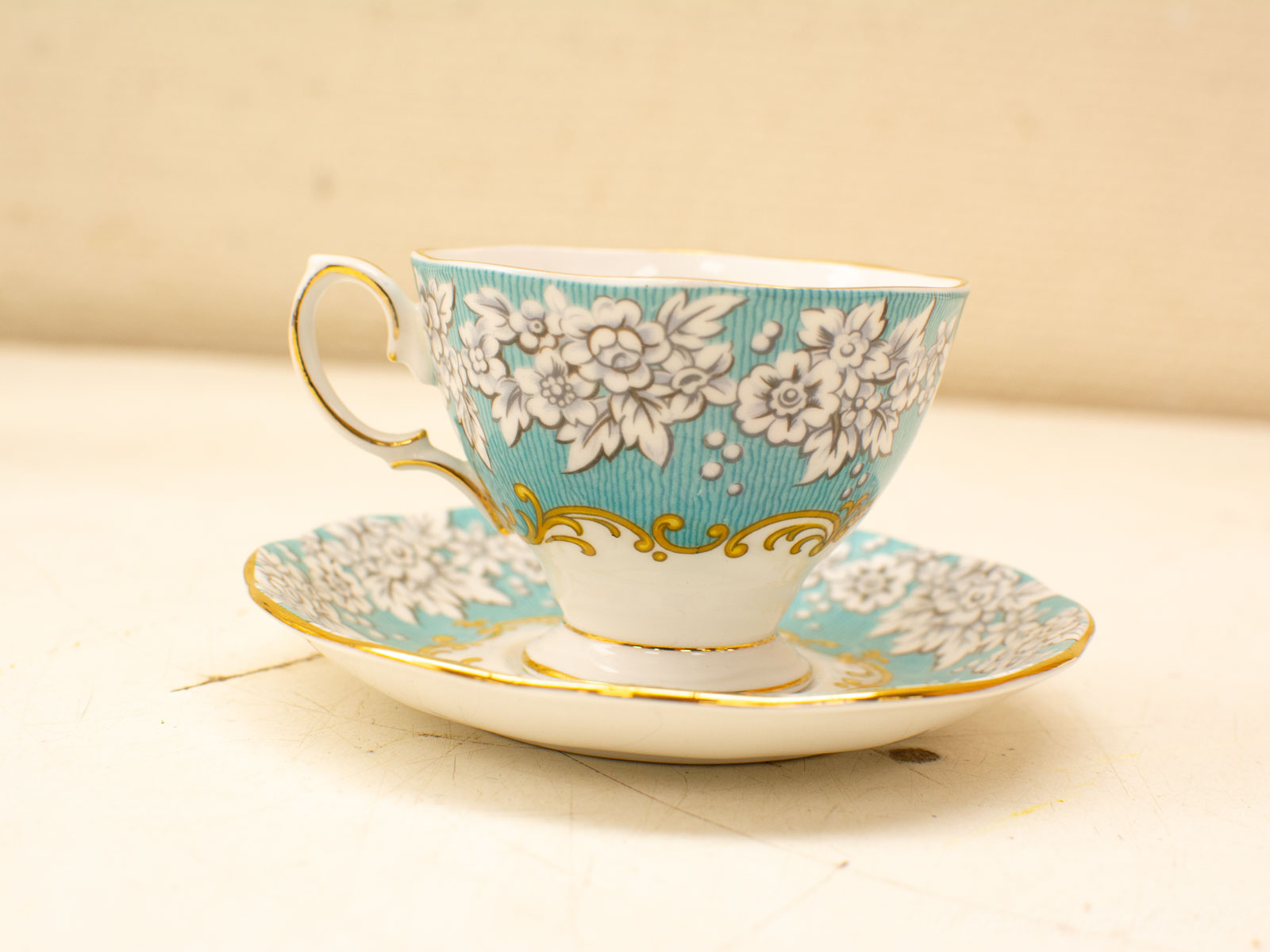 Elegant vintage tea cup and saucer set with turquoise and white floral design.