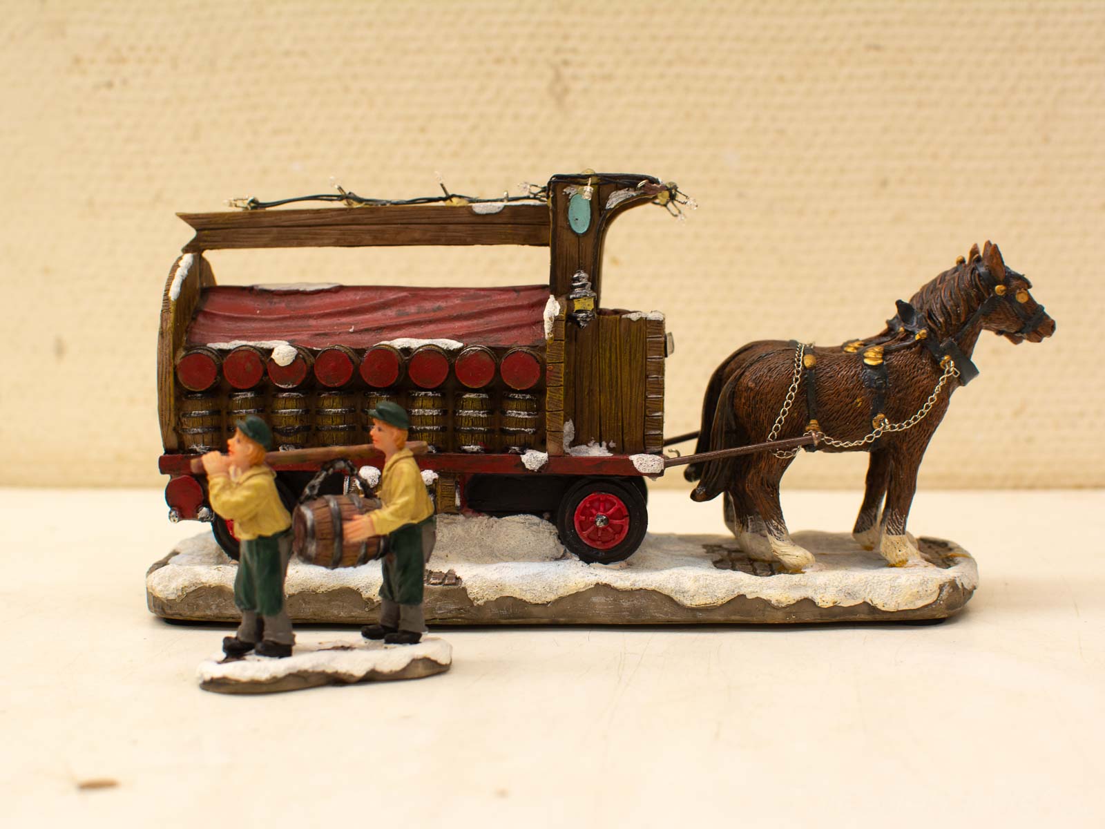 Charming vintage winter wagon scene with figures, horse, and barrels in a snowy landscape.