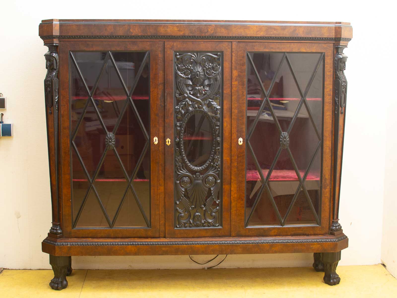 Vintage wooden cabinet with diamond-patterned glass doors and luxurious red velvet interior.