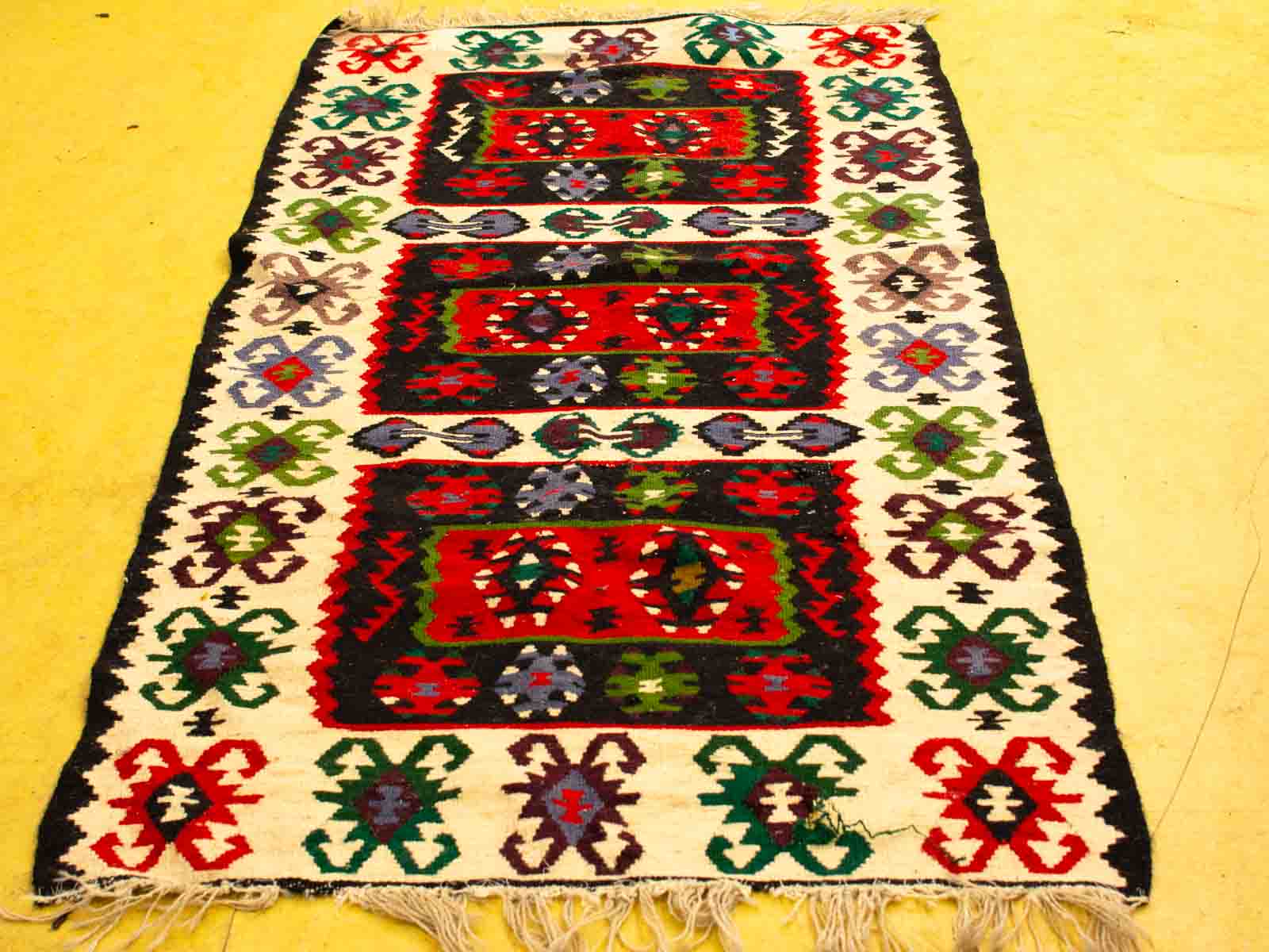 Colorful vintage geometric rug with cultural motifs and handmade fringes for a stunning focal point.