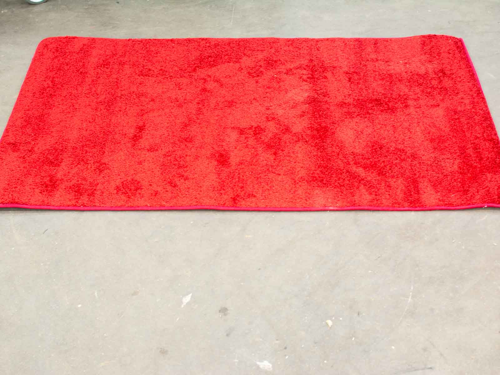 Bright red plush mat on concrete floor enhancing warmth and comfort in a modern interior.