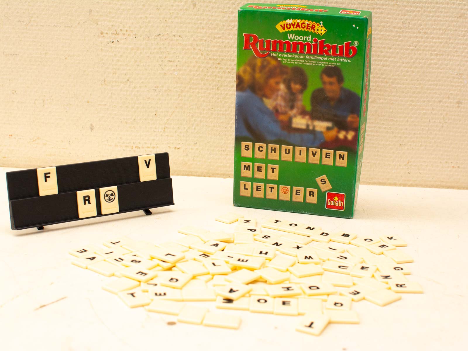 Voyager Woord Rummikub game with scattered yellow tiles and strategic tile holder for family fun night.