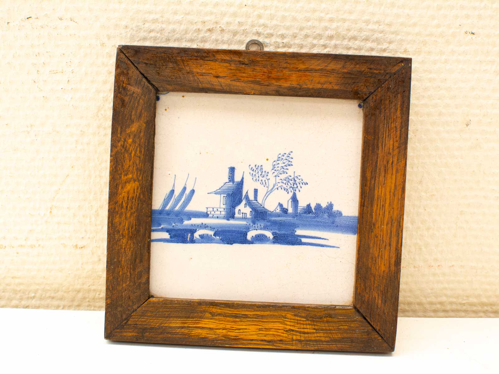 Charming blue-and-white landscape wall art in a rustic wooden frame, perfect for vintage decor.