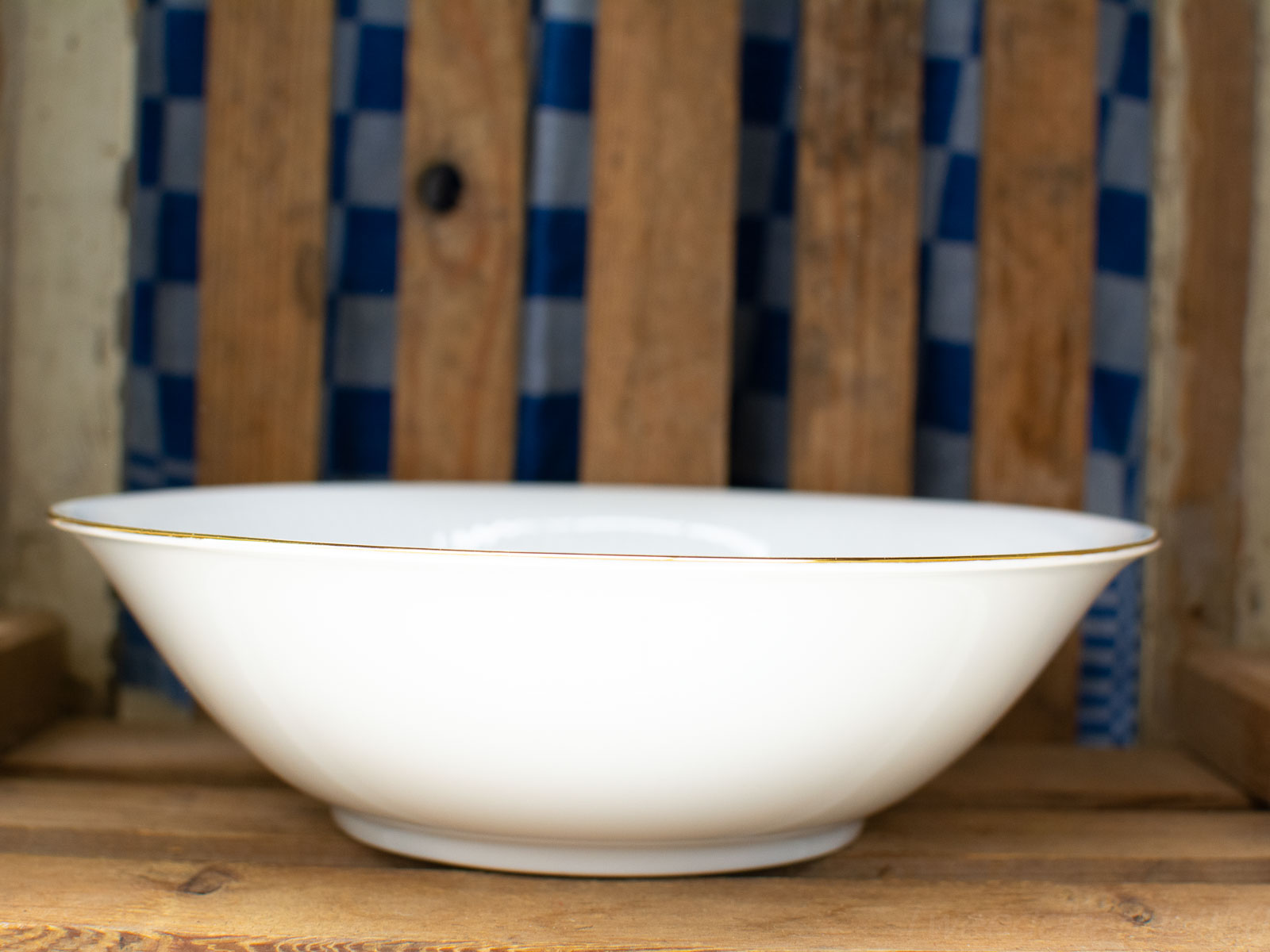 Elegant white bowl with golden rim on rustic wood, perfect for dining and gatherings.