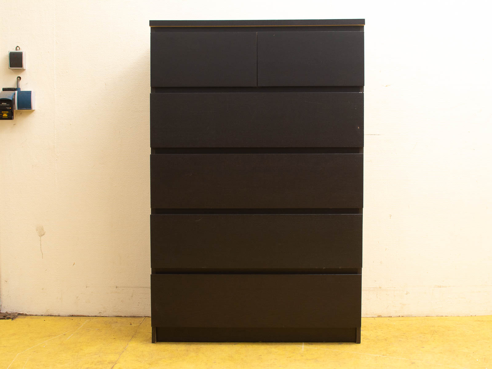 Sleek black dresser with minimalist design and vibrant yellow flooring for modern interiors.