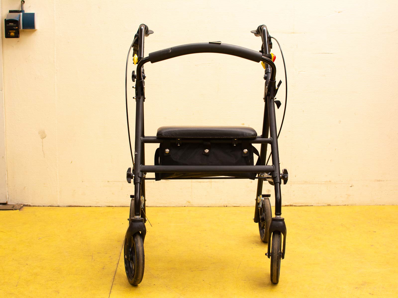 Black mobility walker with comfortable seat, hand brakes, and storage, ideal for daily activities.