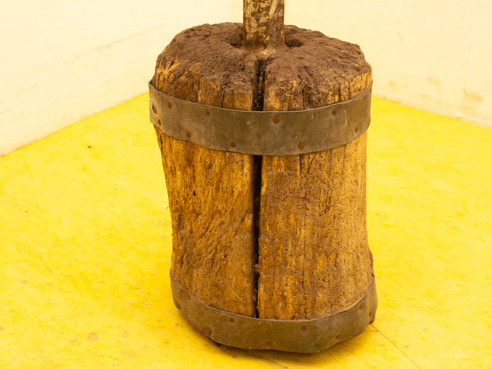 Rustic wooden block with vintage metal band, showcasing traditional craftsmanship on a vibrant yellow floor.