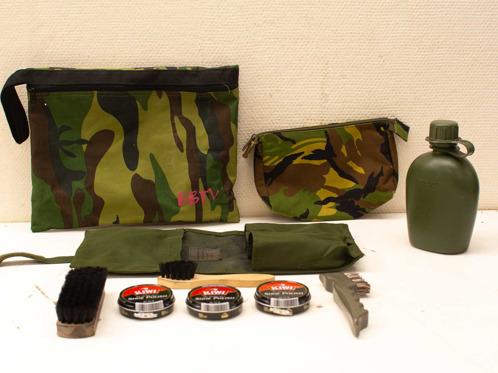 Military-themed accessories: camouflage pouches, cleaning supplies, and a water canteen for outdoor readiness.