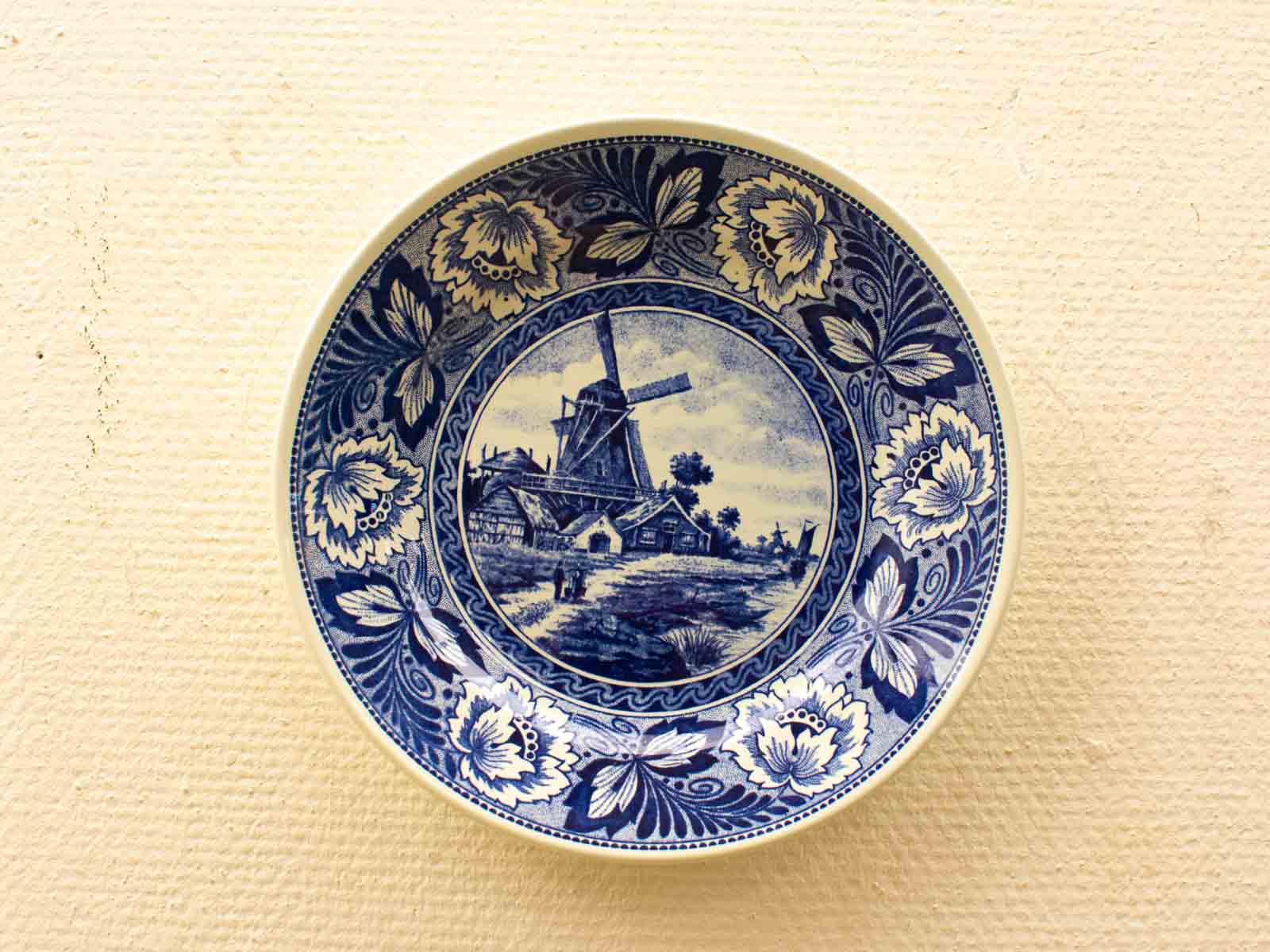 Intricate blue and white ceramic plate featuring a windmill landscape and floral designs.