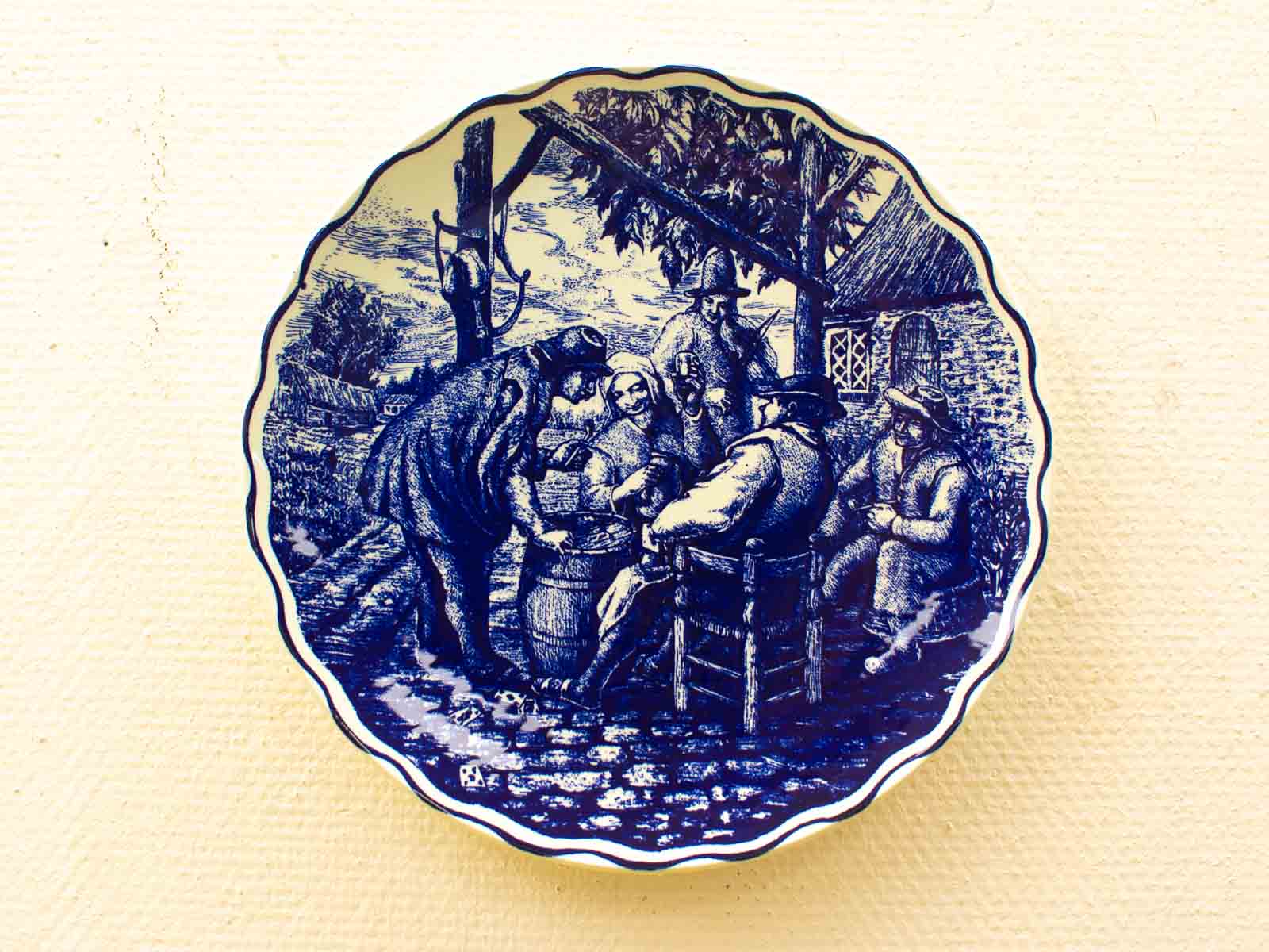 Decorative blue and white plate showcasing a vibrant historical outdoor scene with engaging figures.