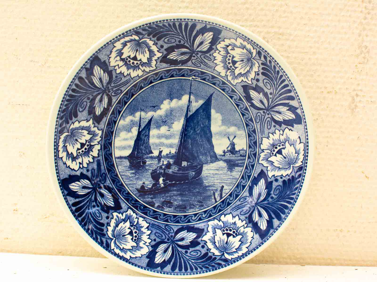 Elegant blue and white decorative plate with sailing boats and floral motifs.