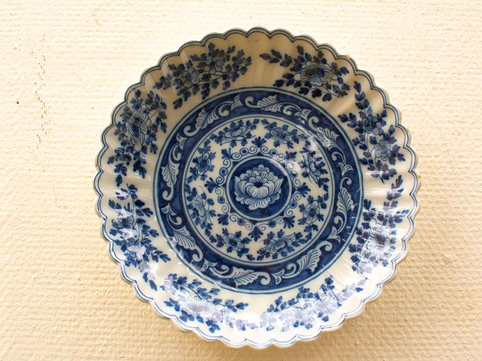 Elegant blue and white ceramic plate with scalloped edges and intricate floral designs.