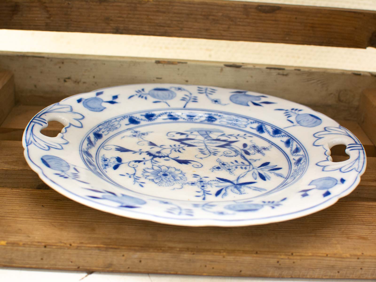 Elegant ceramic plate with blue floral design, scalloped edges, and practical handles.