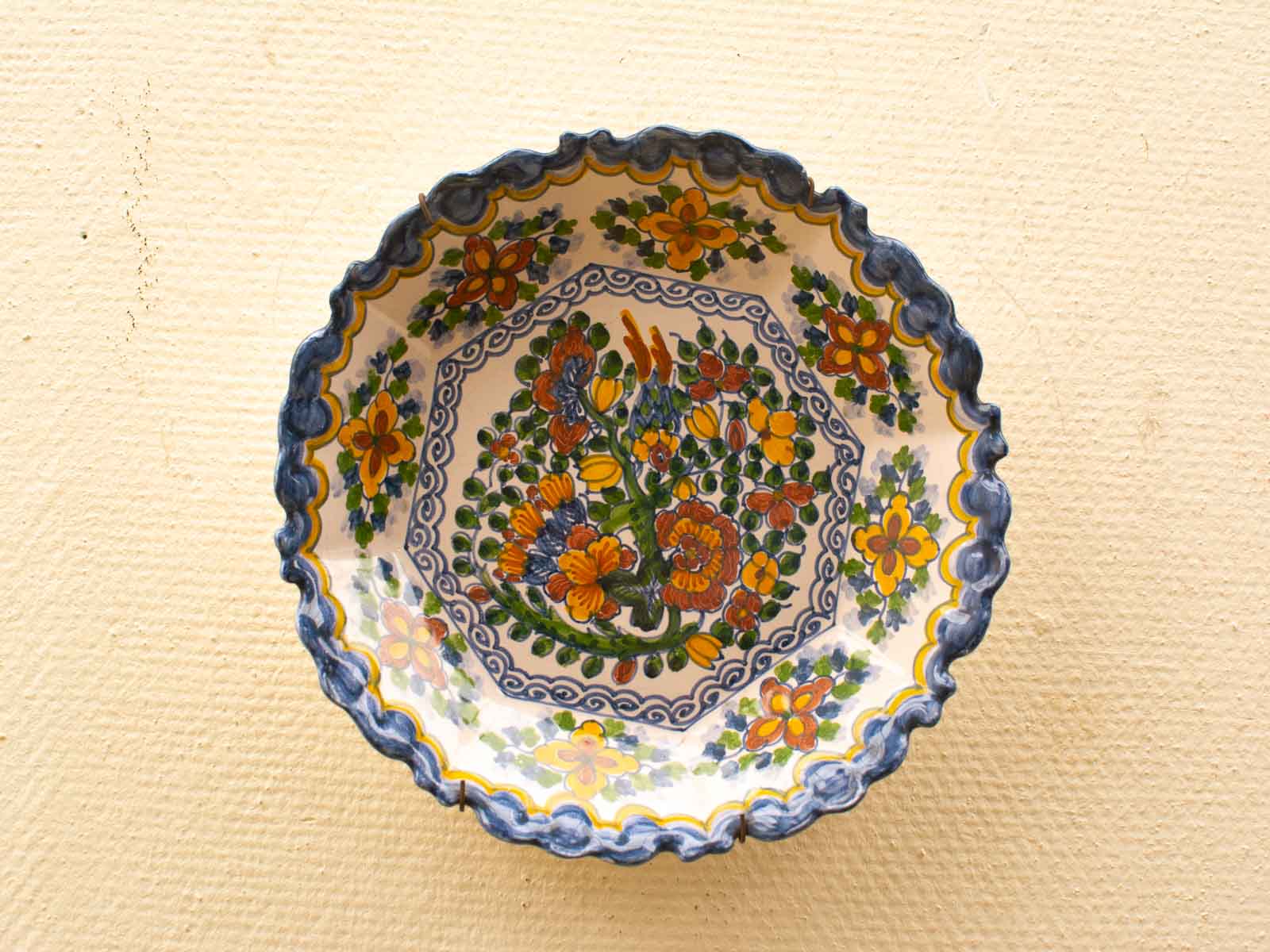 Vibrant hand-painted scalloped ceramic bowl with intricate floral designs, perfect for home decor.