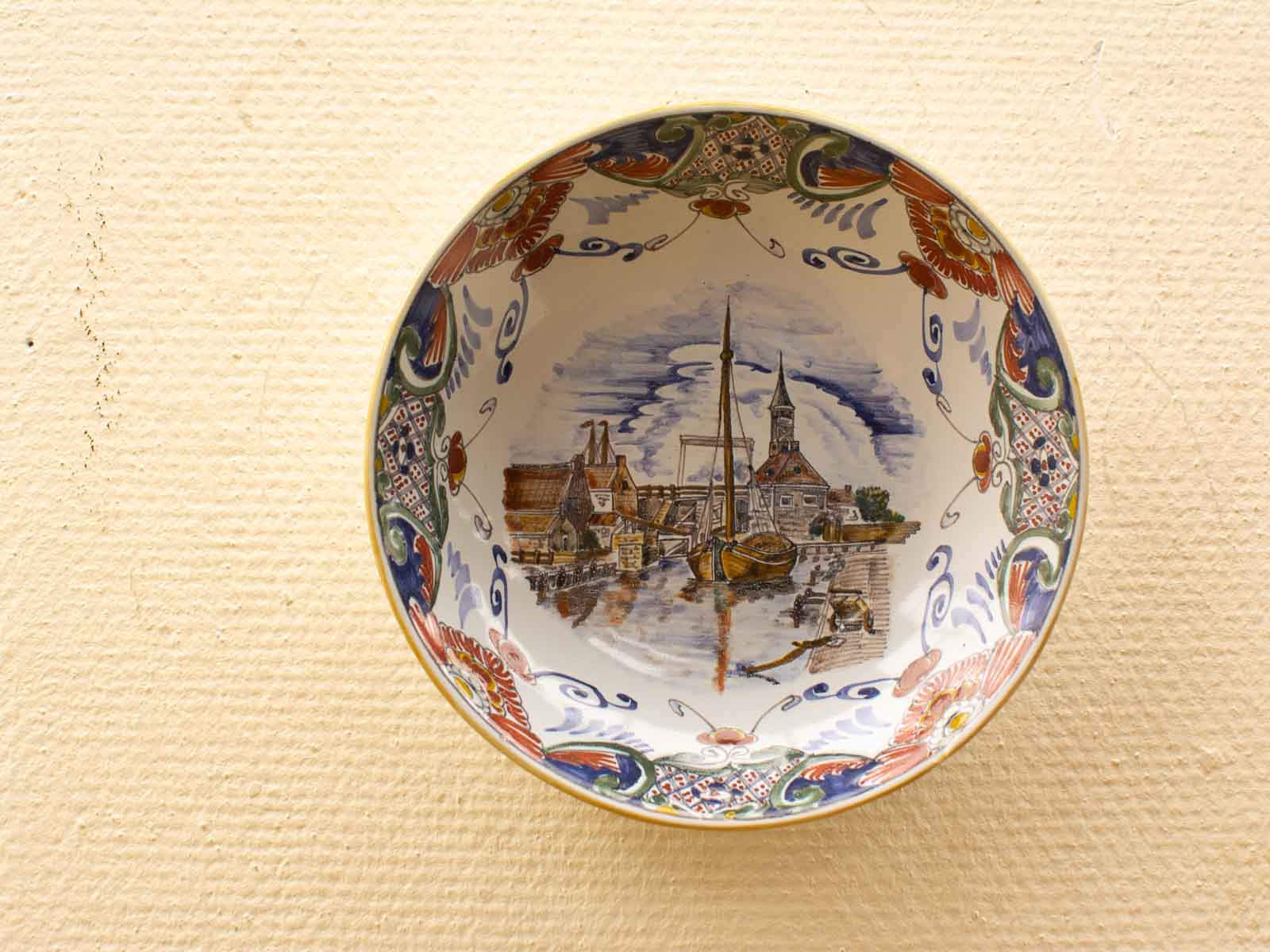 Vibrant vintage plate showcasing a serene waterfront village with intricate colorful designs.