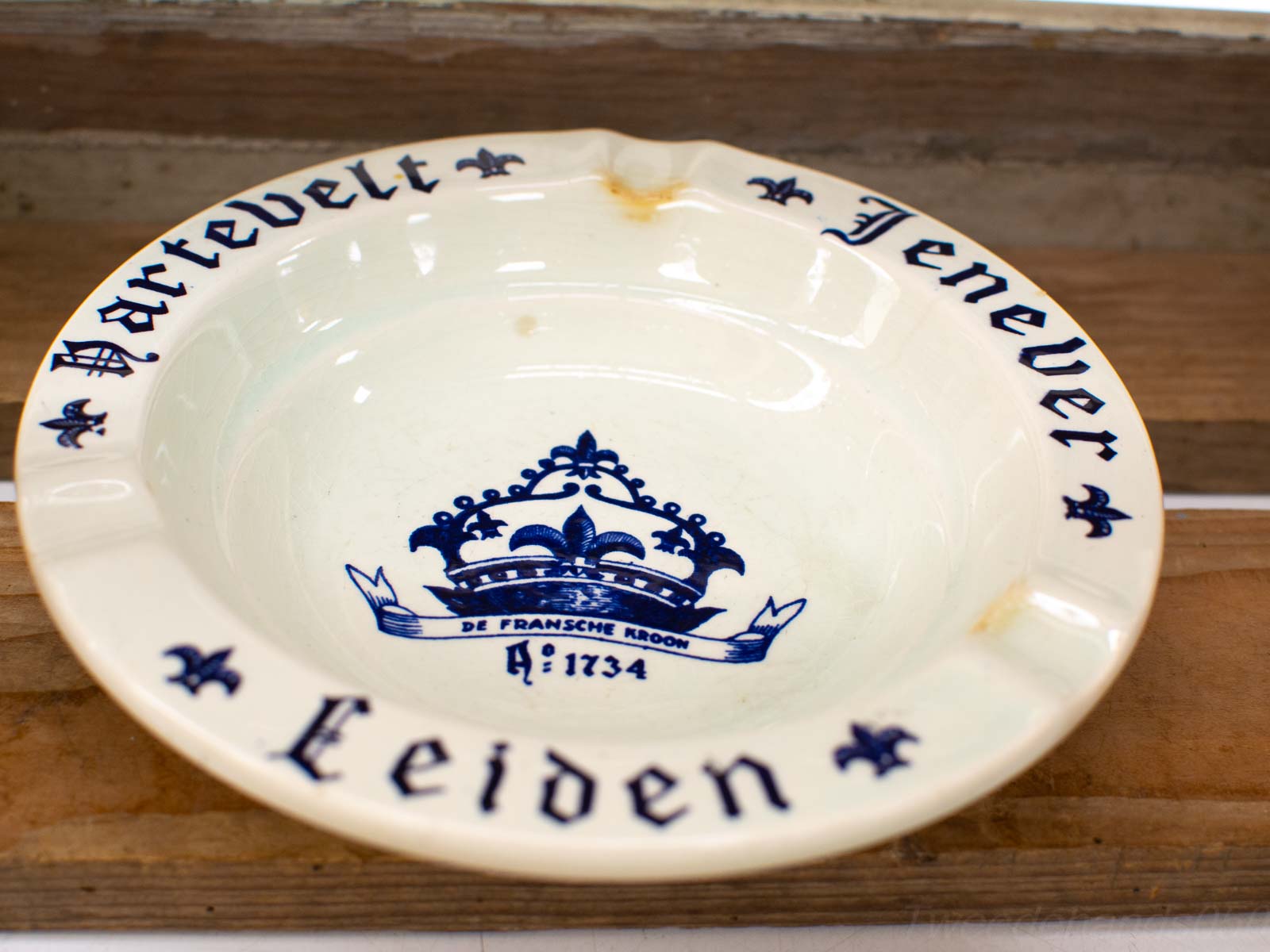 Vintage cream dish with crown motif, “DE FRANSCHE KROON 1734,” showcasing Dutch craftsmanship.