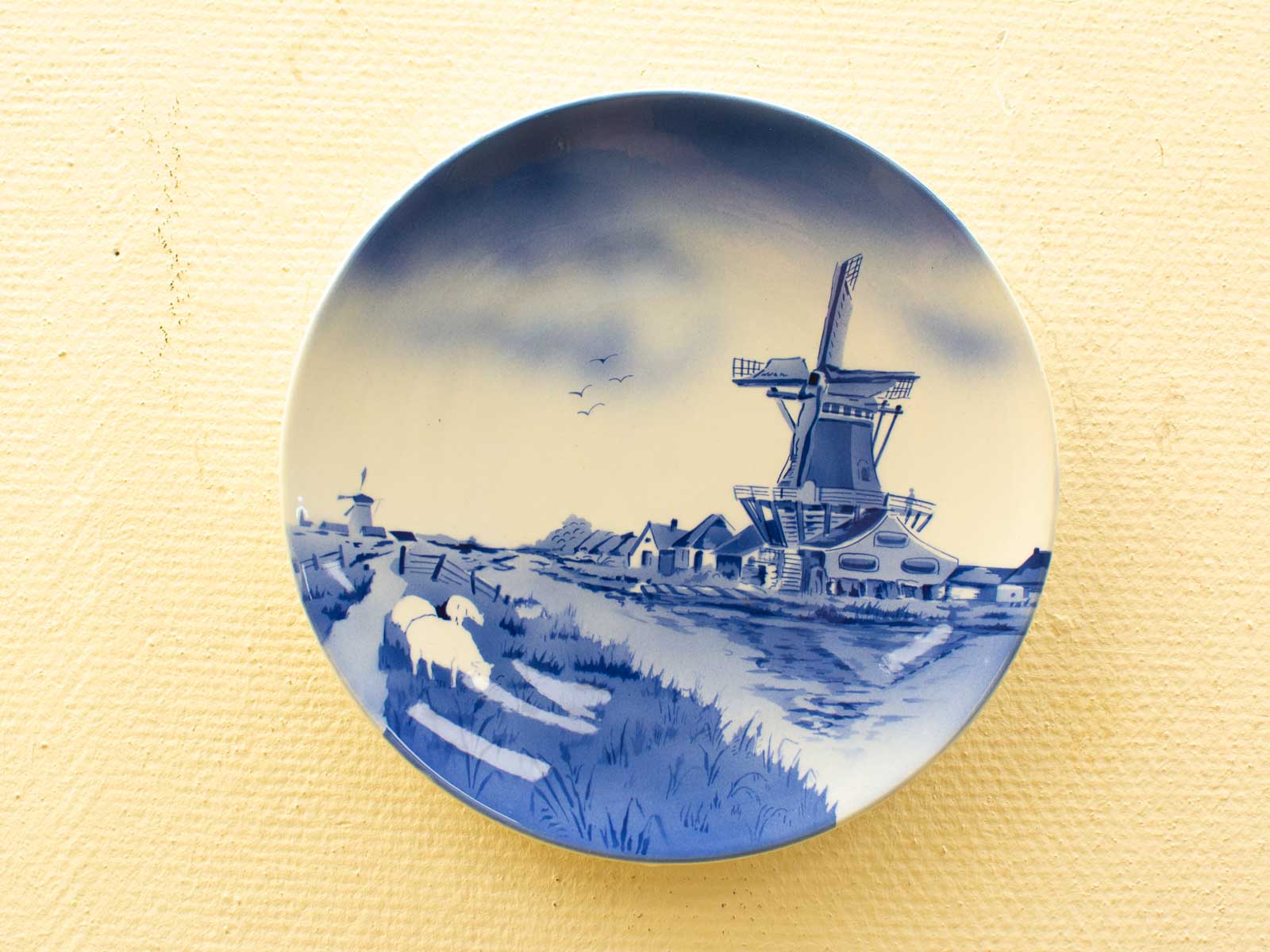 Tranquil Dutch landscape plate featuring sheep and windmill in blue and white design.