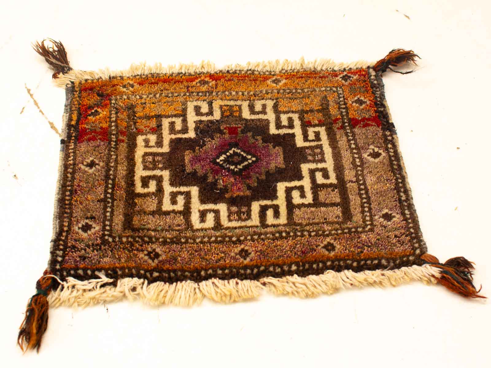 Vintage rug with diamond motif in purple and black, adorned with warm earth tones.