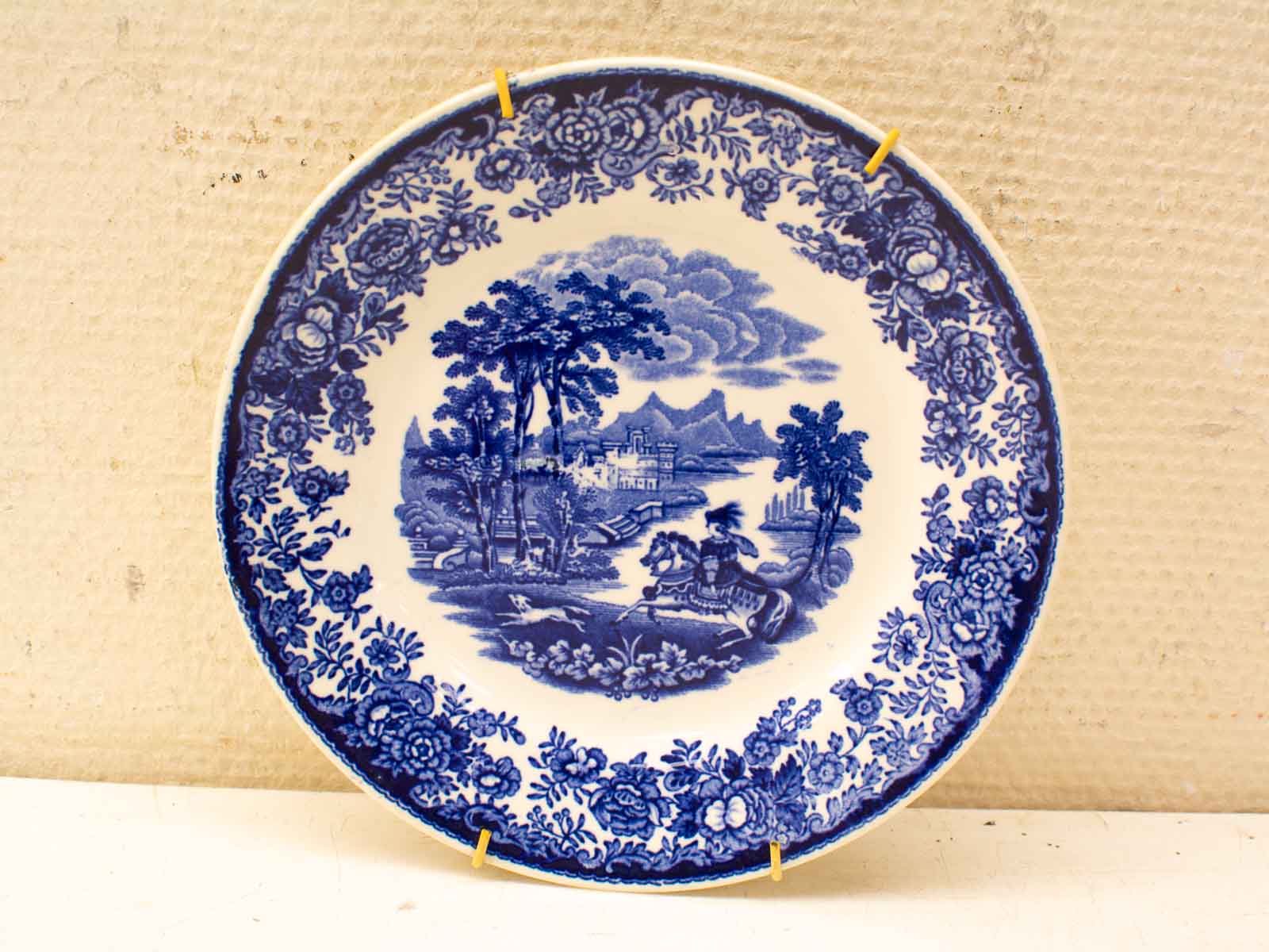 Serene blue transferware plate featuring a countryside scene with floral border and horseback rider.