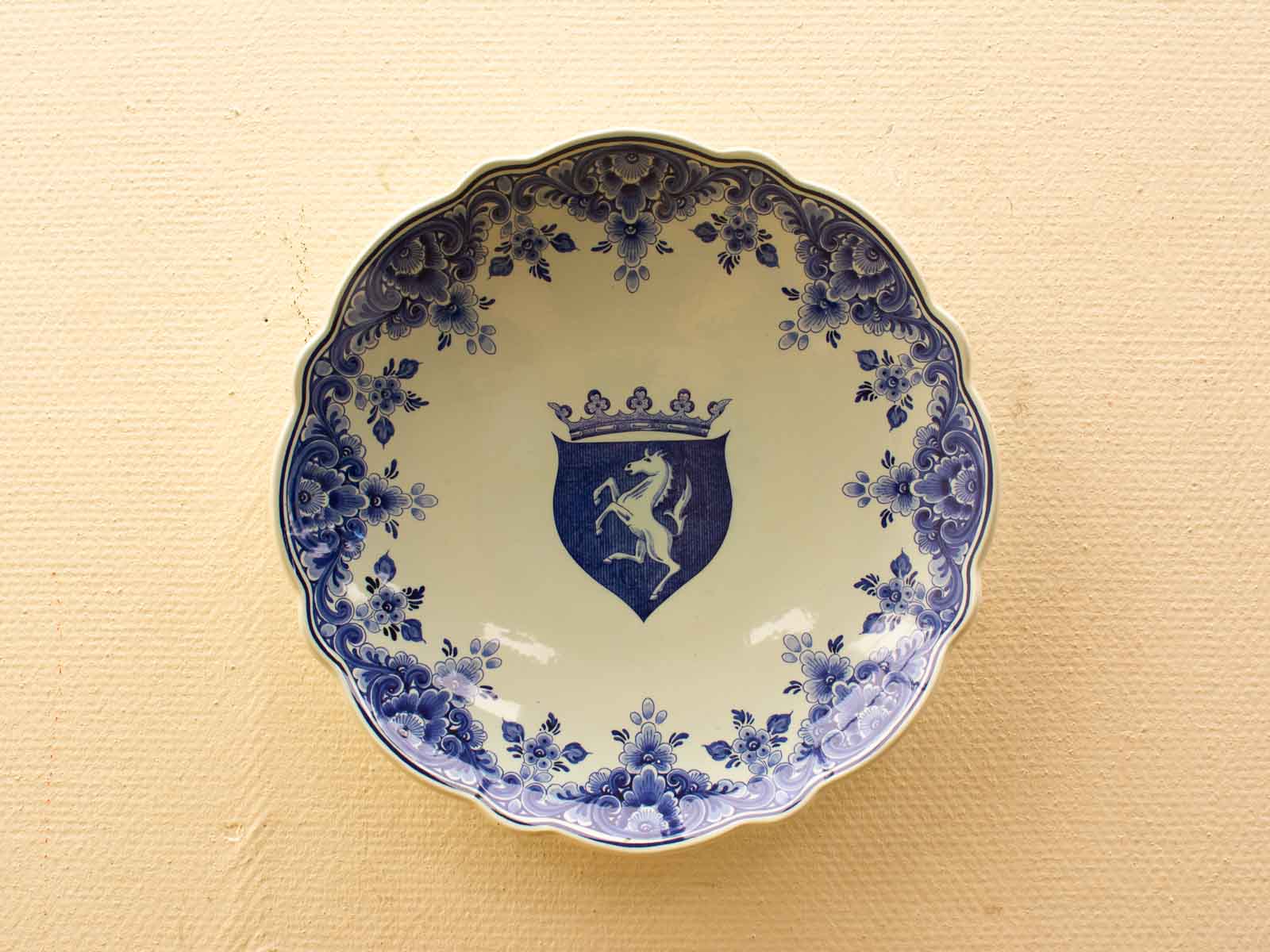 Elegant porcelain plate with rearing horse coat of arms and intricate floral designs in blue.