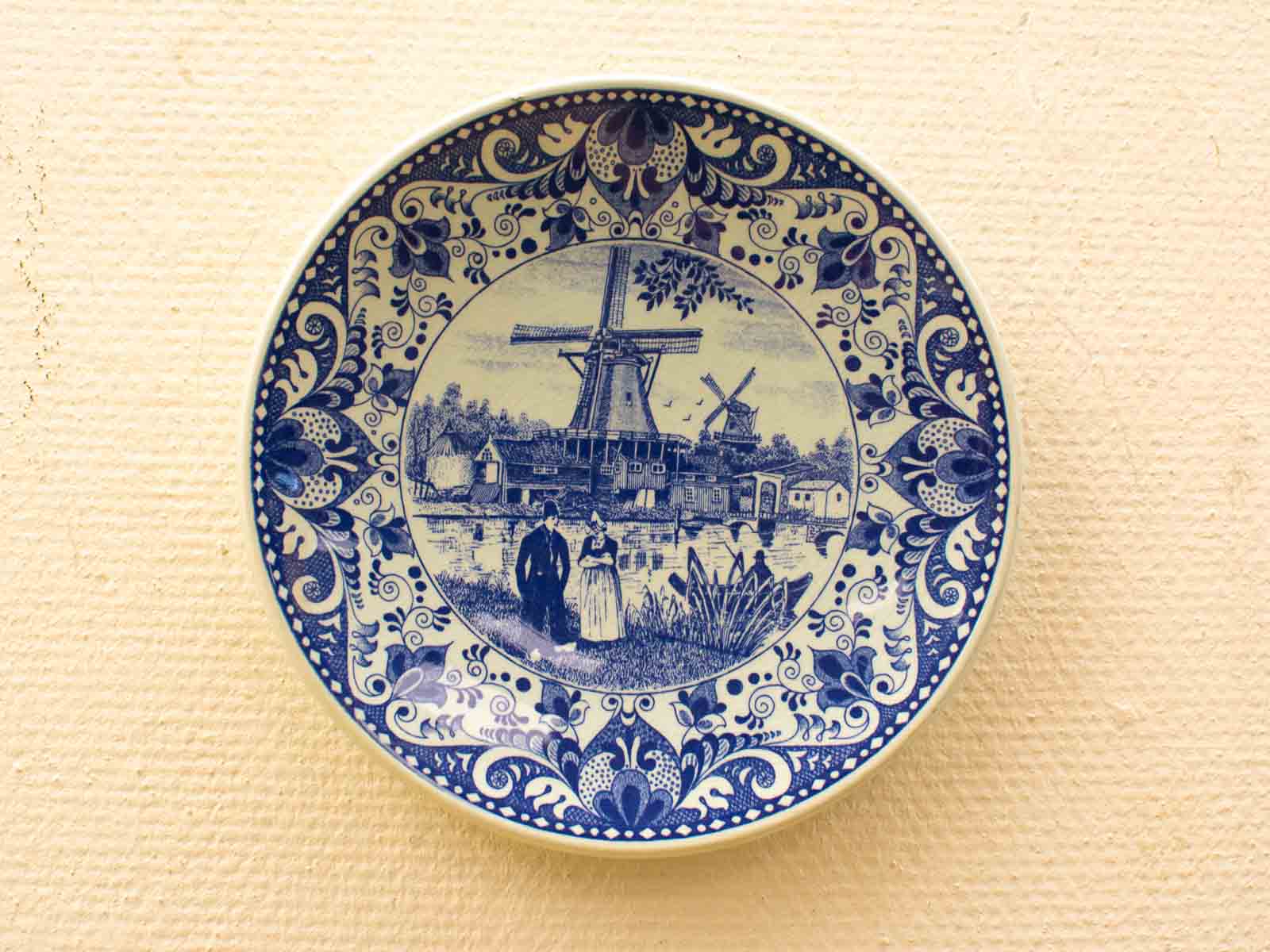 Delft Blue ceramic plate showcasing a windmill and village, embodying Dutch cultural heritage.