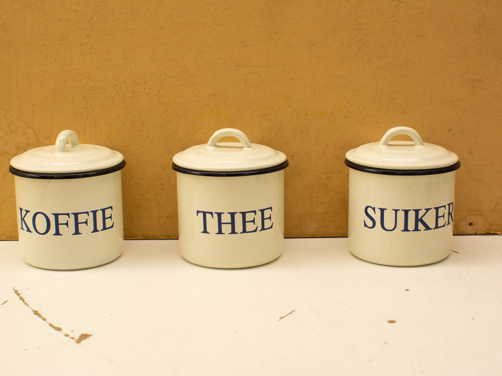 Charming vintage ceramic canisters for coffee, tea, and sugar, featuring glossy finishes and blue labels.