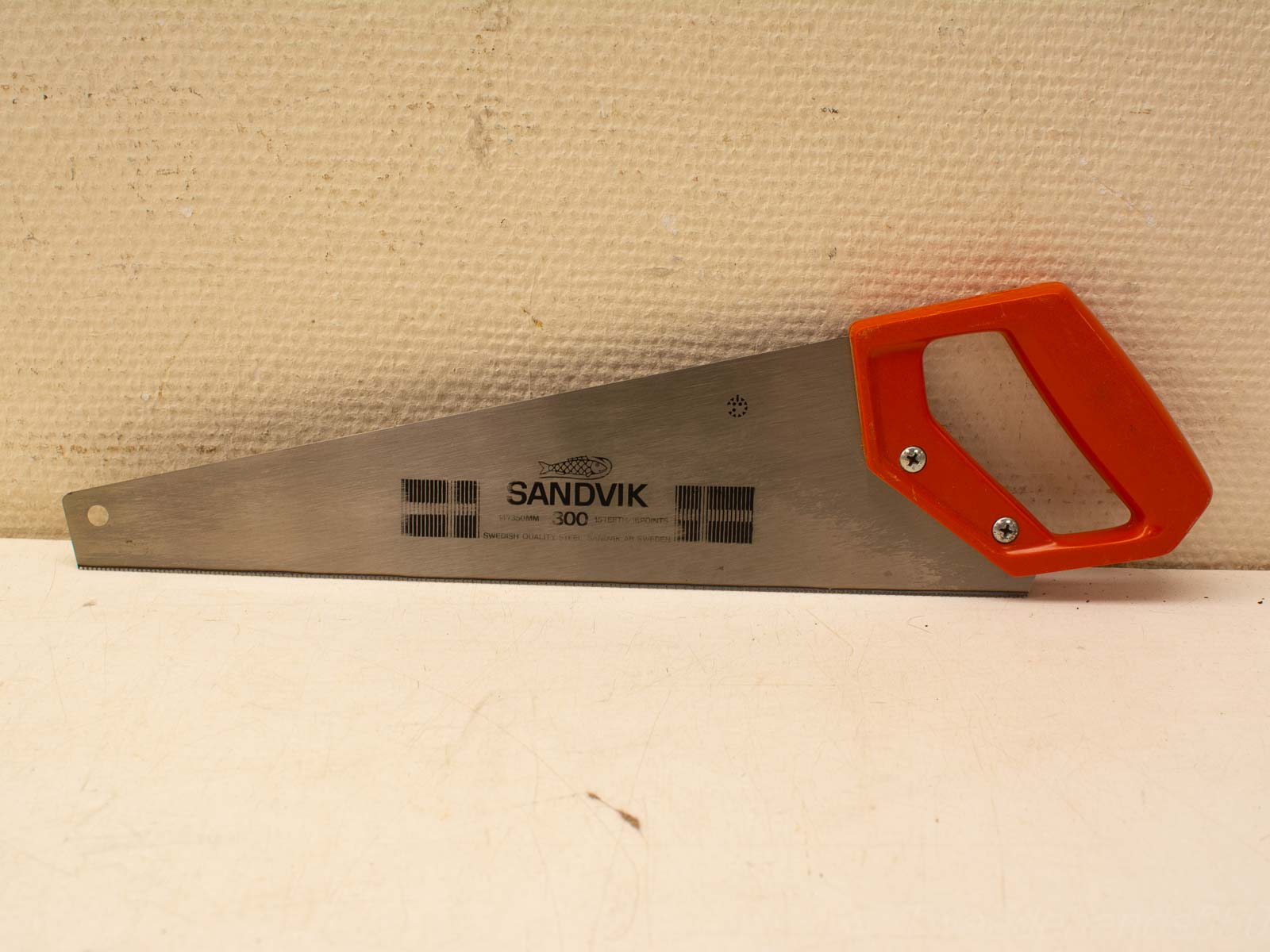 Stylish hand saw with stainless steel blade and ergonomic orange handle for precision cutting.